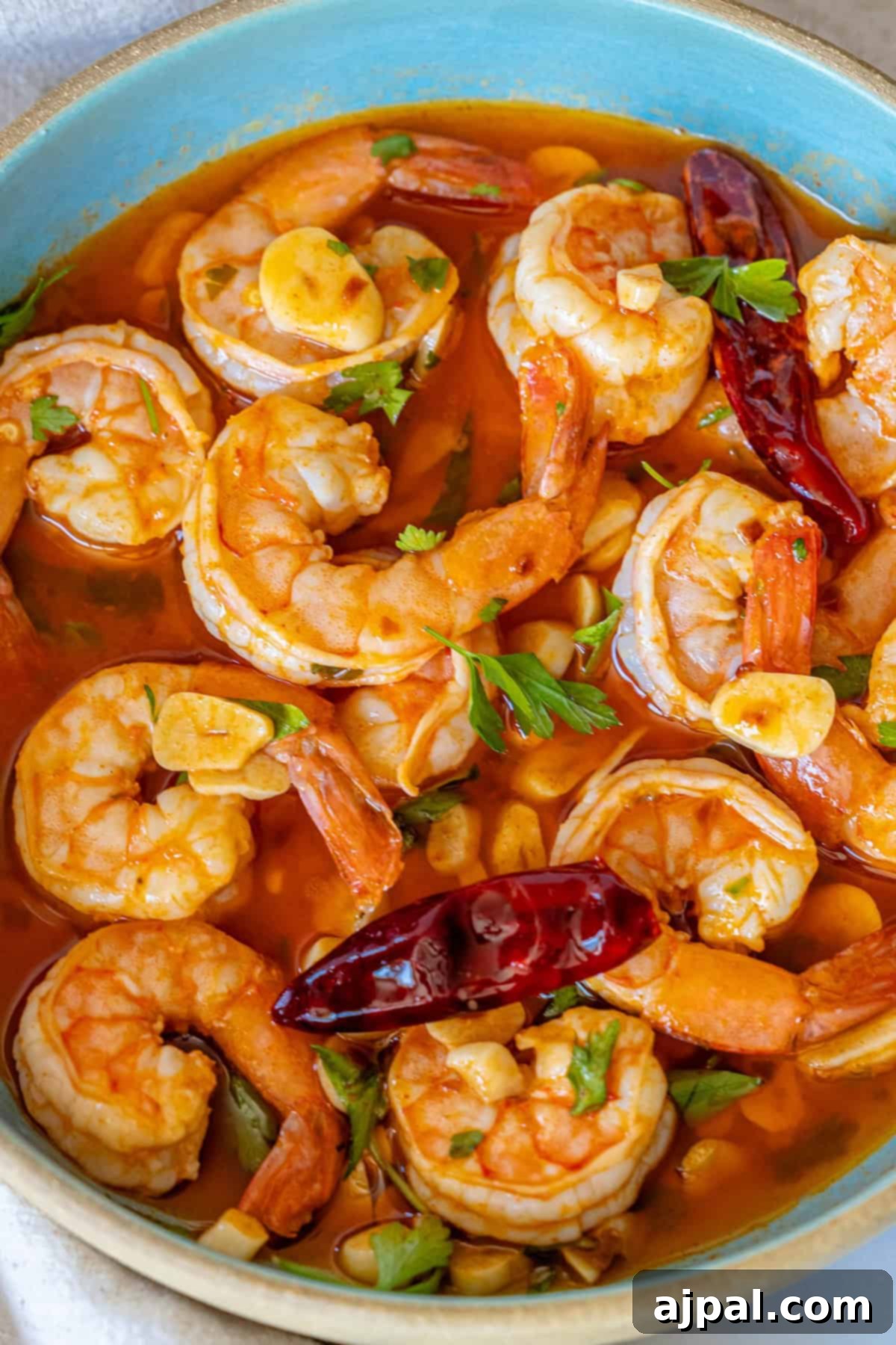Finished Gambas Pil Pil dish garnished with fresh parsley, served directly from the pan.