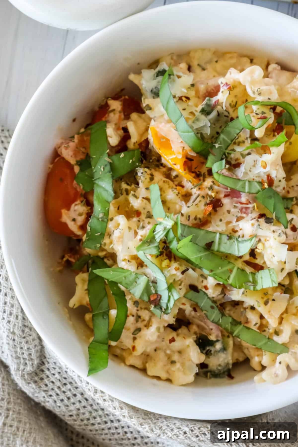 Baked Feta Pasta Bliss 11 A white bowl filled with creamy macaroni and cheese, topped with chopped fresh basil and a mix of red and yellow cherry tomatoes.