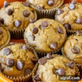 Muffins topped with chocolate chips arranged in a pile on a tray.