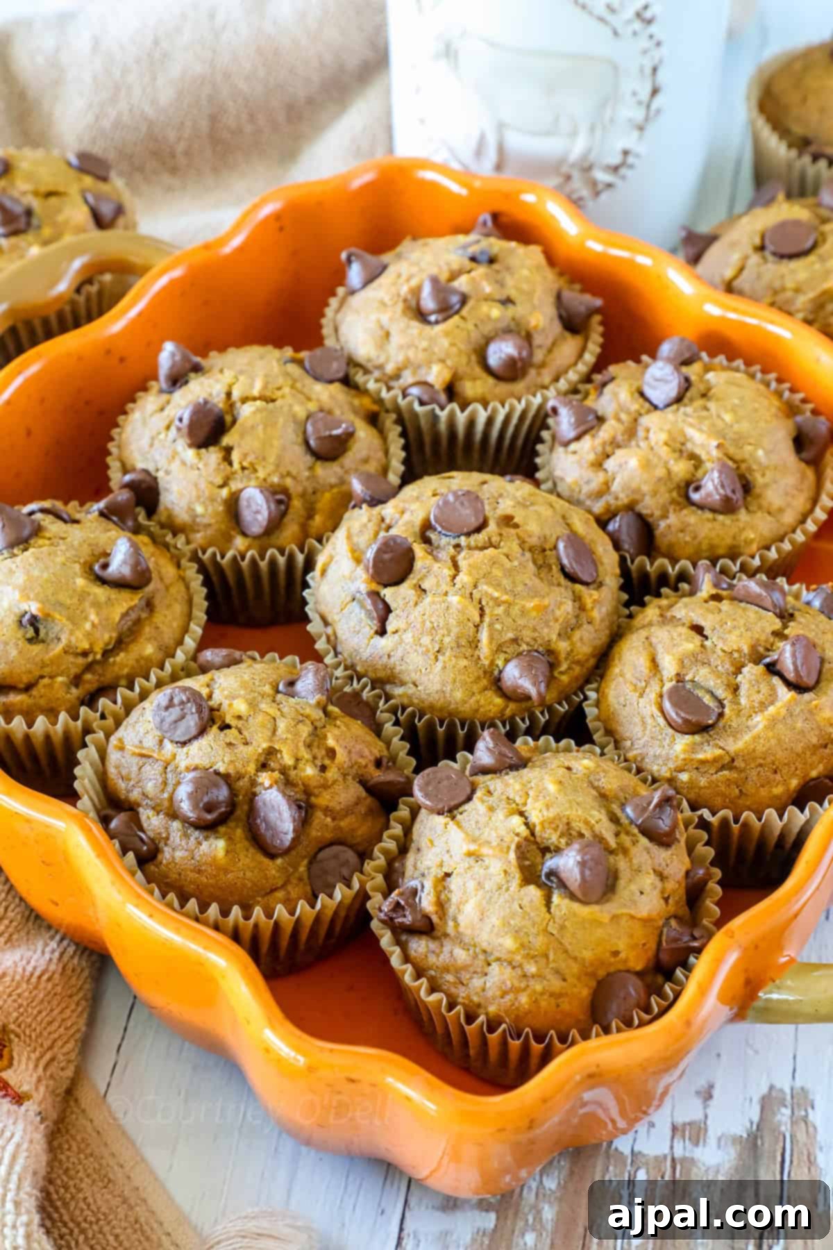A tray of freshly baked pumpkin chocolate chip muffins displayed in a decorative orange dish.