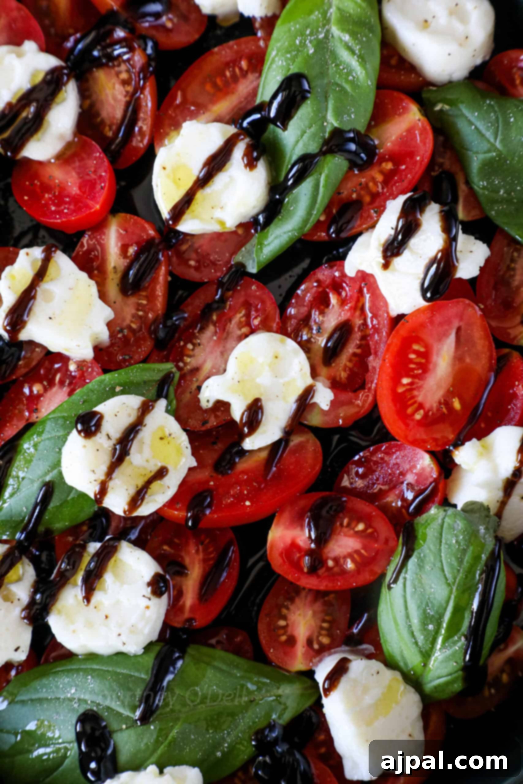 A close-up shot of a Spooky Caprese Salad, showcasing the detailed mozzarella ghosts, vibrant cherry tomatoes, and fresh basil leaves, all glistening with balsamic glaze. The focus is on the delicious texture and festive shapes.