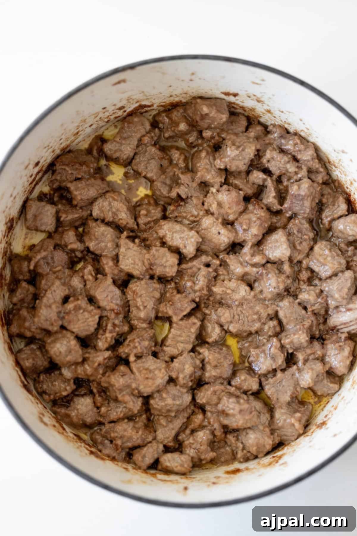Simple Beef Stew 7 A pot filled with browned, cubed pieces of beef in a light sauce, perfect for a classic beef stew.