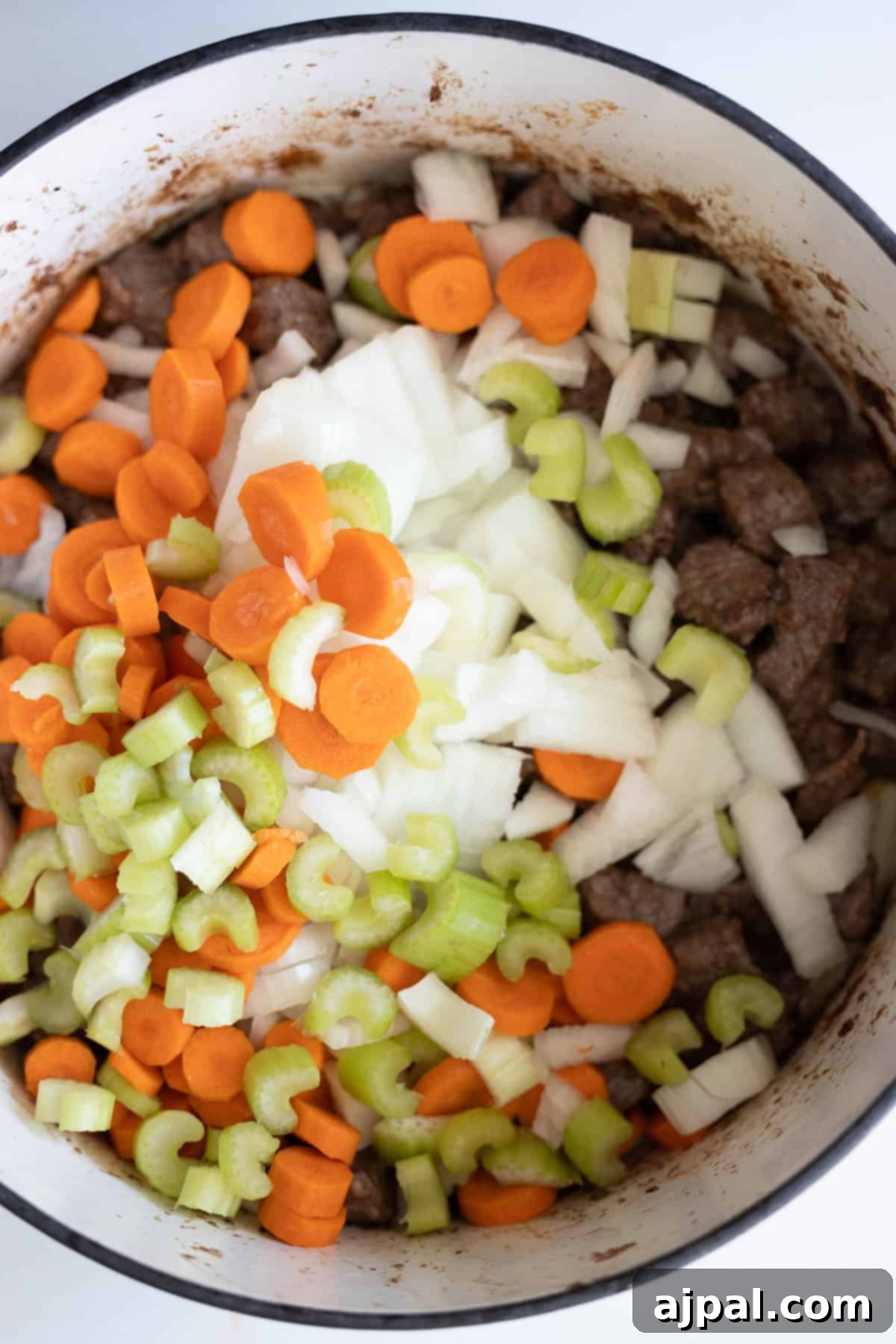 Simple Beef Stew 8 A pot filled with sliced carrots, celery, onions, and tender beef pieces is ready for further cooking into a hearty beef stew.