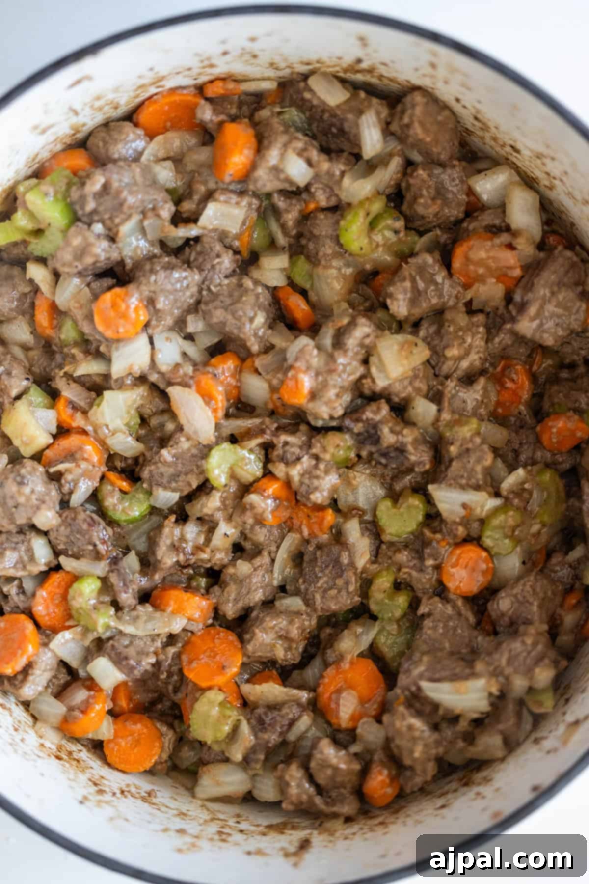 Simple Beef Stew 9 A close-up of a pot filled with a mixture of diced beef, carrots, celery, and onions, creating a classic beef stew.