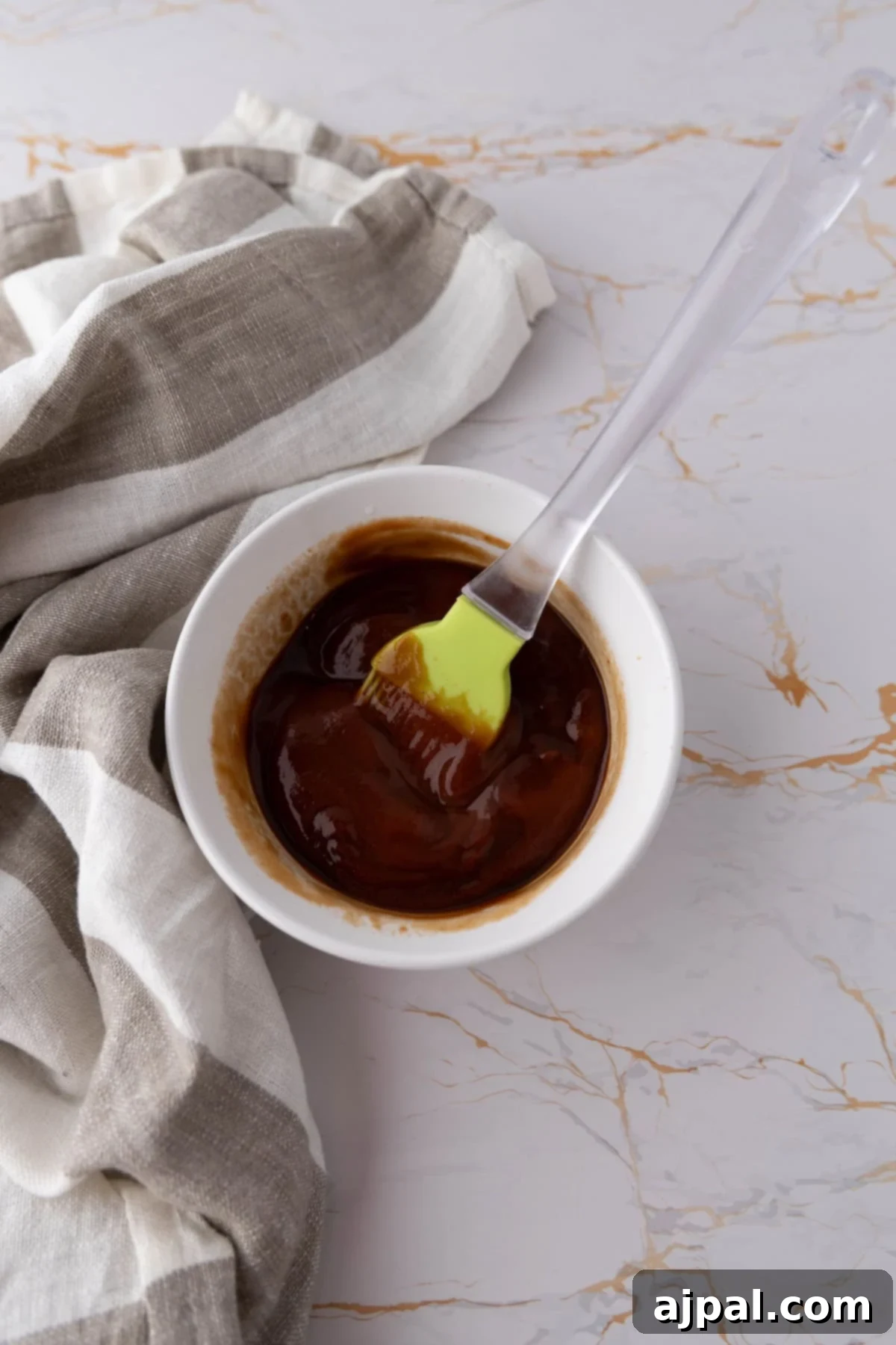 A bowl of barbecue sauce with a silicone brush, ready for glazing a savory mummy meatloaf.