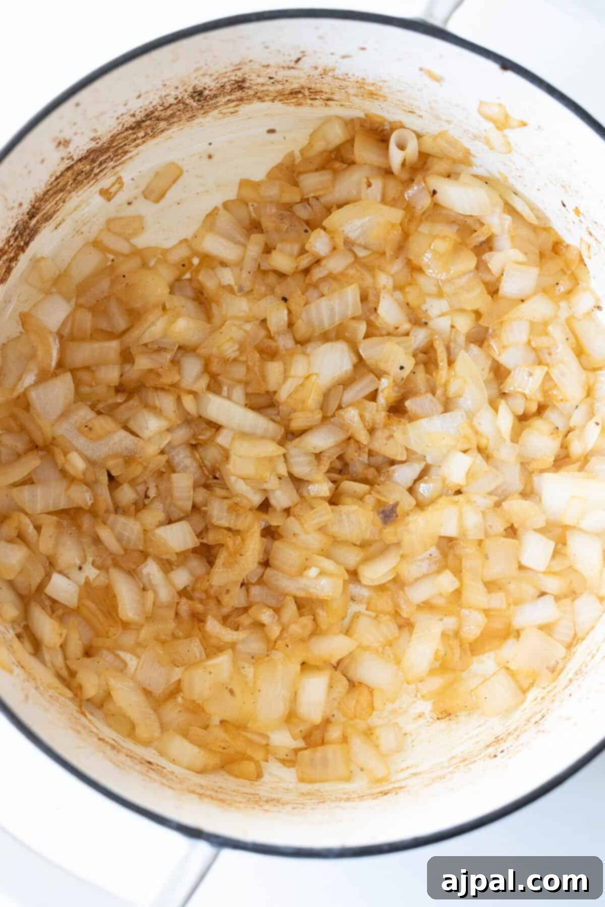Chopped onions are gently sautéing in a pot, becoming lightly browned and translucent, forming an aromatic and flavorful base for the hearty beef stew.