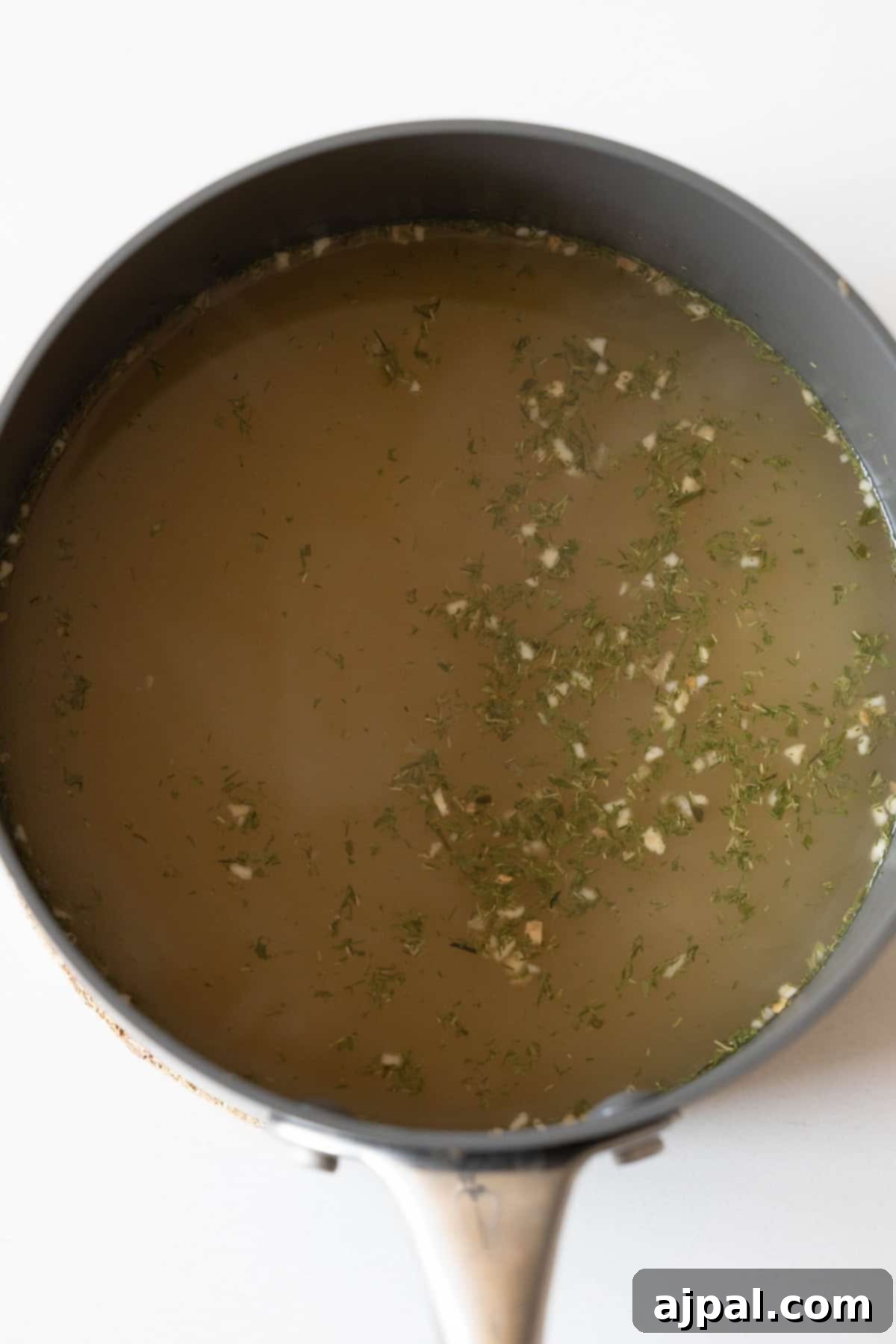 Authentic Couscous Delights 6 A delightful recipe: a pot of broth with herbs floating on the surface, perfect to make your dish flavorful.