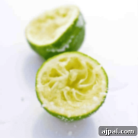 Two halves of a squeezed lime are shown on a white surface, with some lime pulp and juice visible, perfect for your Salted Lime Tequila Shooters.