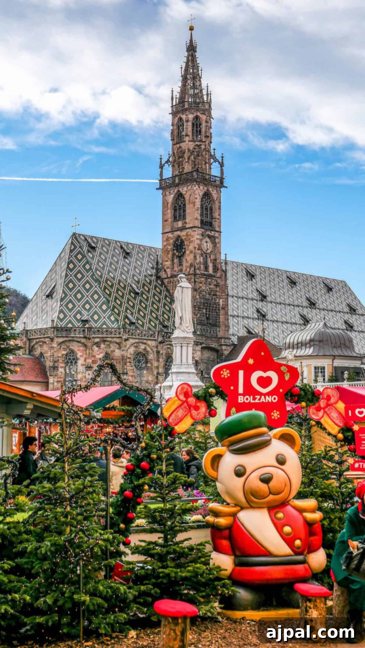 Bolzano's Magical Christmas Market 2 A festive Christmas market featuring decorated trees and a large bear statue stands proudly in front of Bolzano's historic church.