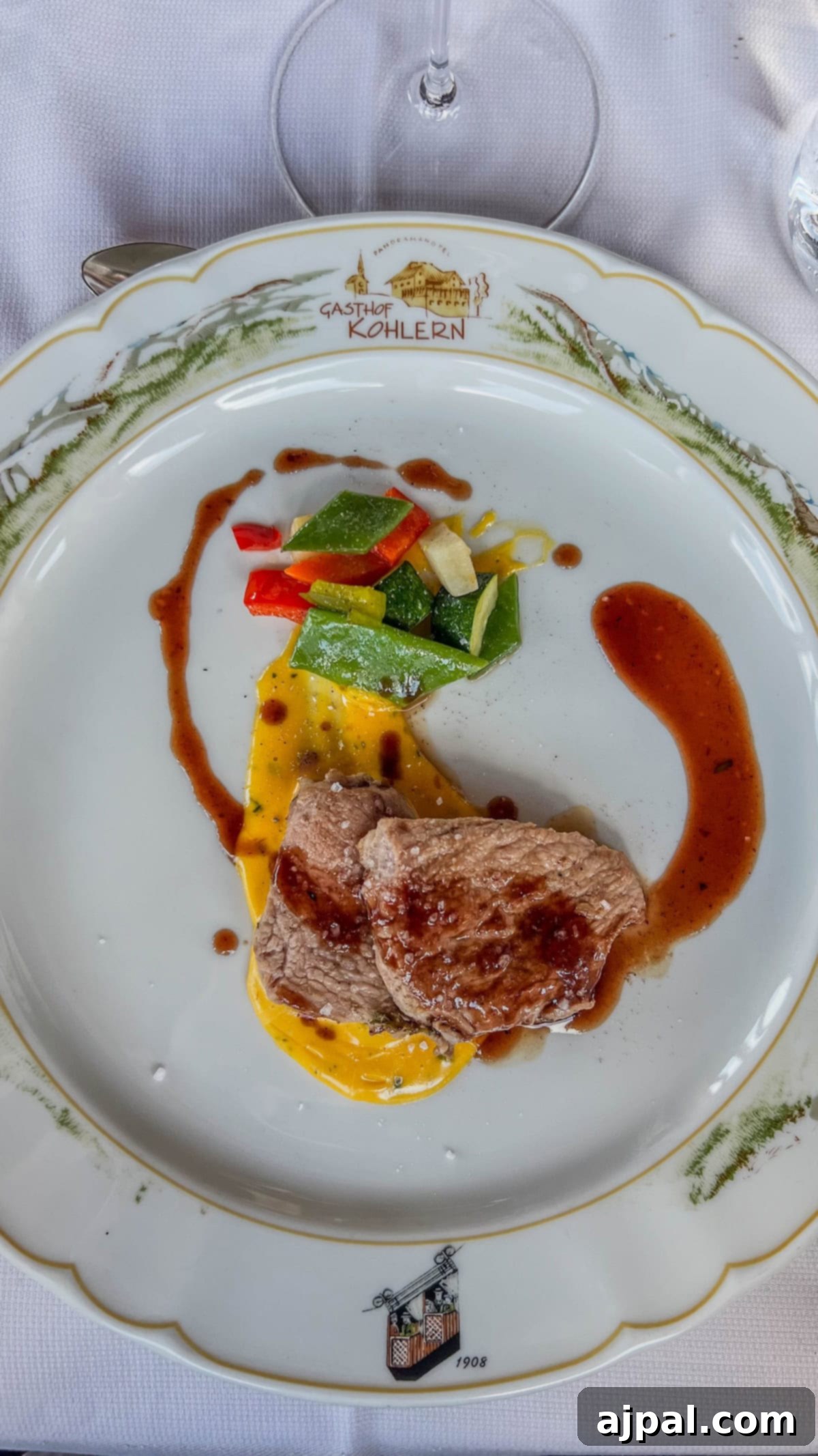 Bolzano's Magical Christmas Market 21 A plated dish with sliced meat and sauce, accompanied by colorful vegetables, garnished with a drizzle of sauce on a decorative plate that evokes the festive charm of the Bolzano Christmas Market.