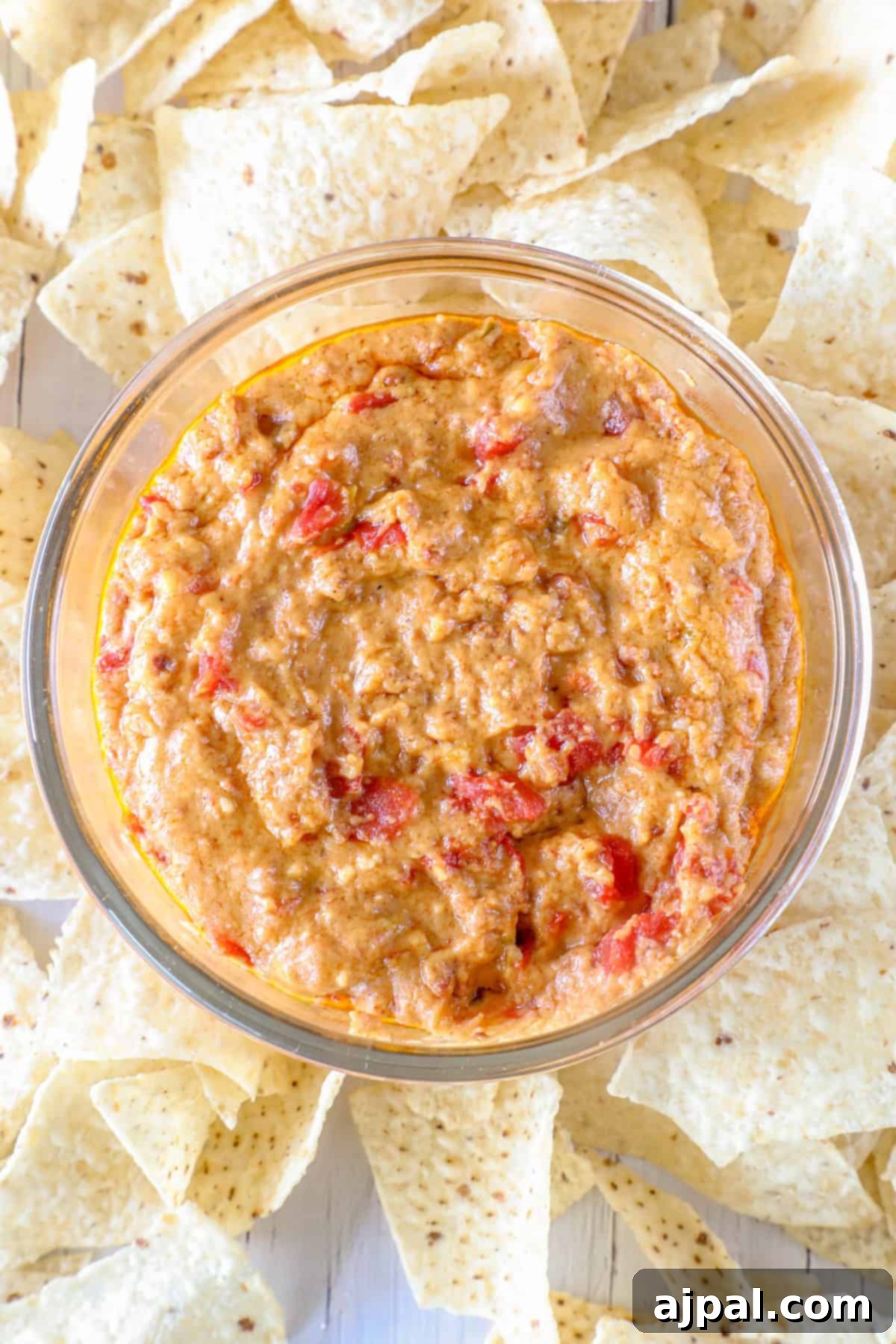 Decadent Smoked Chorizo Queso 4 A bowl of smoky chorizo-infused queso dip with red peppers, surrounded by crispy tortilla chips.