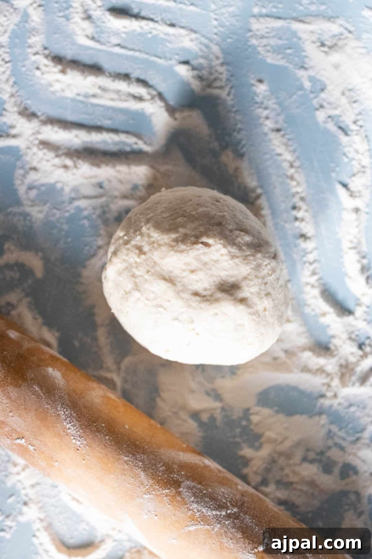 Classic Scottish Tattie Scones 9 A ball of dough rests on a floured surface with a wooden rolling pin nearby, ready to be transformed into delicious Scottish Tattie Scones.