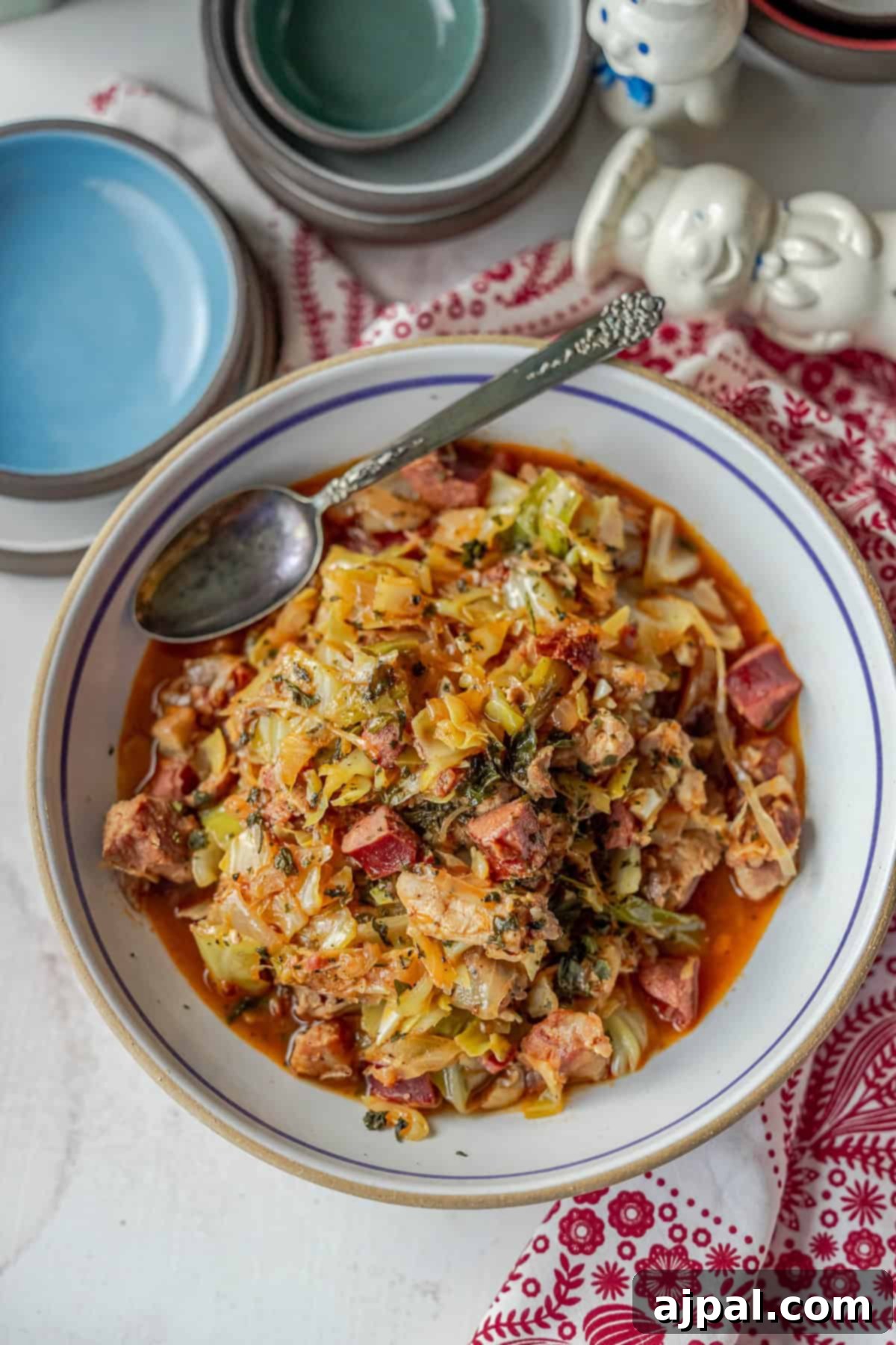 A steaming bowl of traditional Polish Bigos, rich with tender meats and vegetables, served on a red patterned cloth. The hearty hunter's stew is ready to be enjoyed with a spoon.