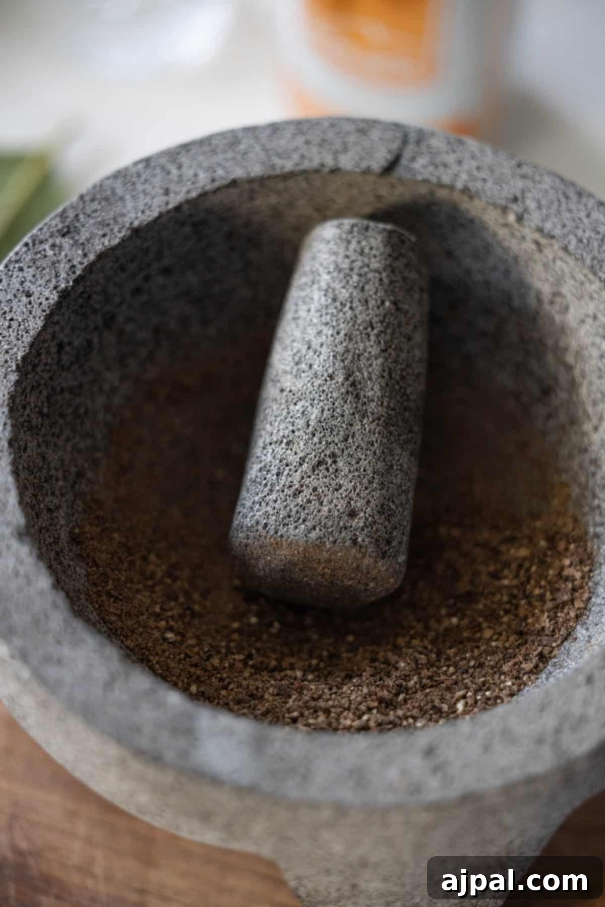 A stone mortar and pestle containing freshly ground spices, ready to enhance the robust flavors of traditional dishes like Polish Bigos.