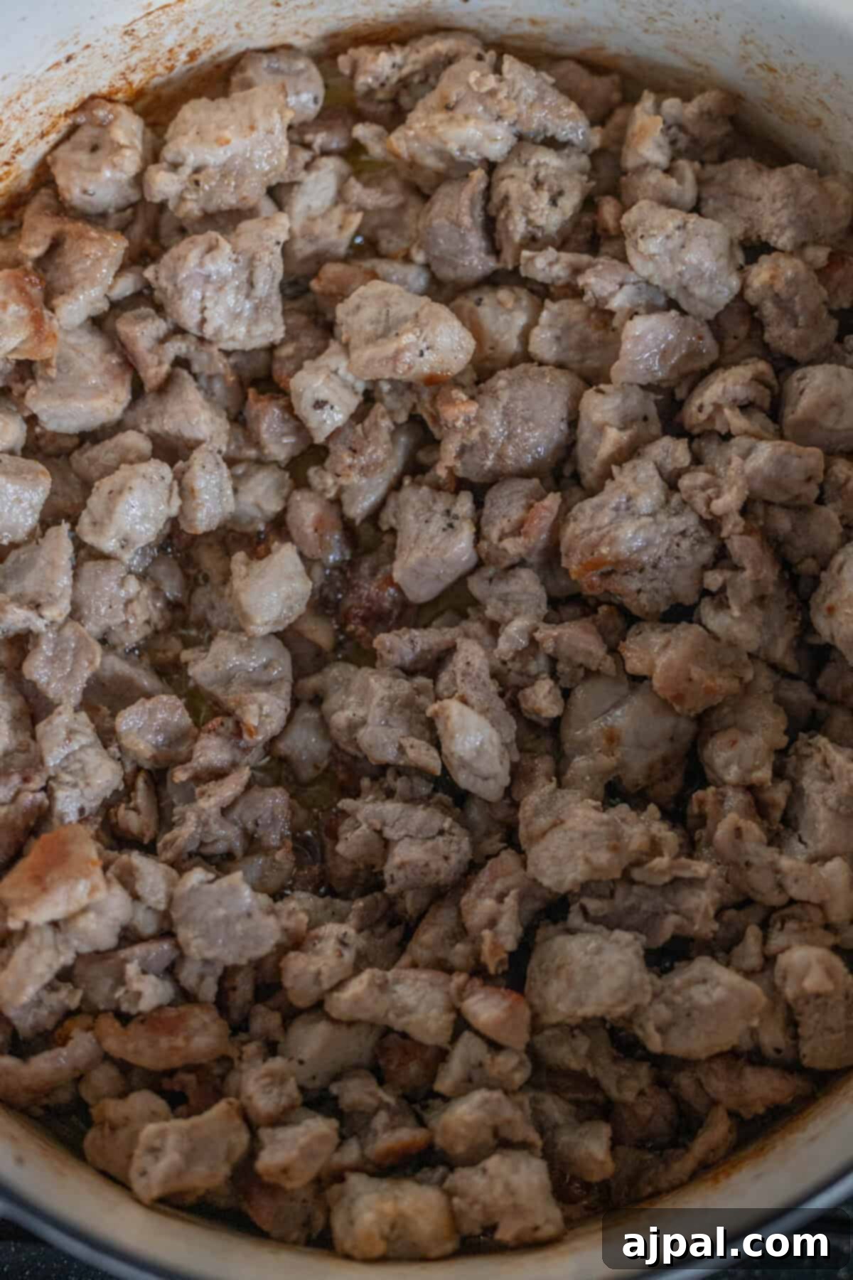 A hearty pot of Polish Bigos, also known as Hunter's Stew, brimming with tender chunks of cooked meat and rich, melded flavors, promising a warm and comforting dish.