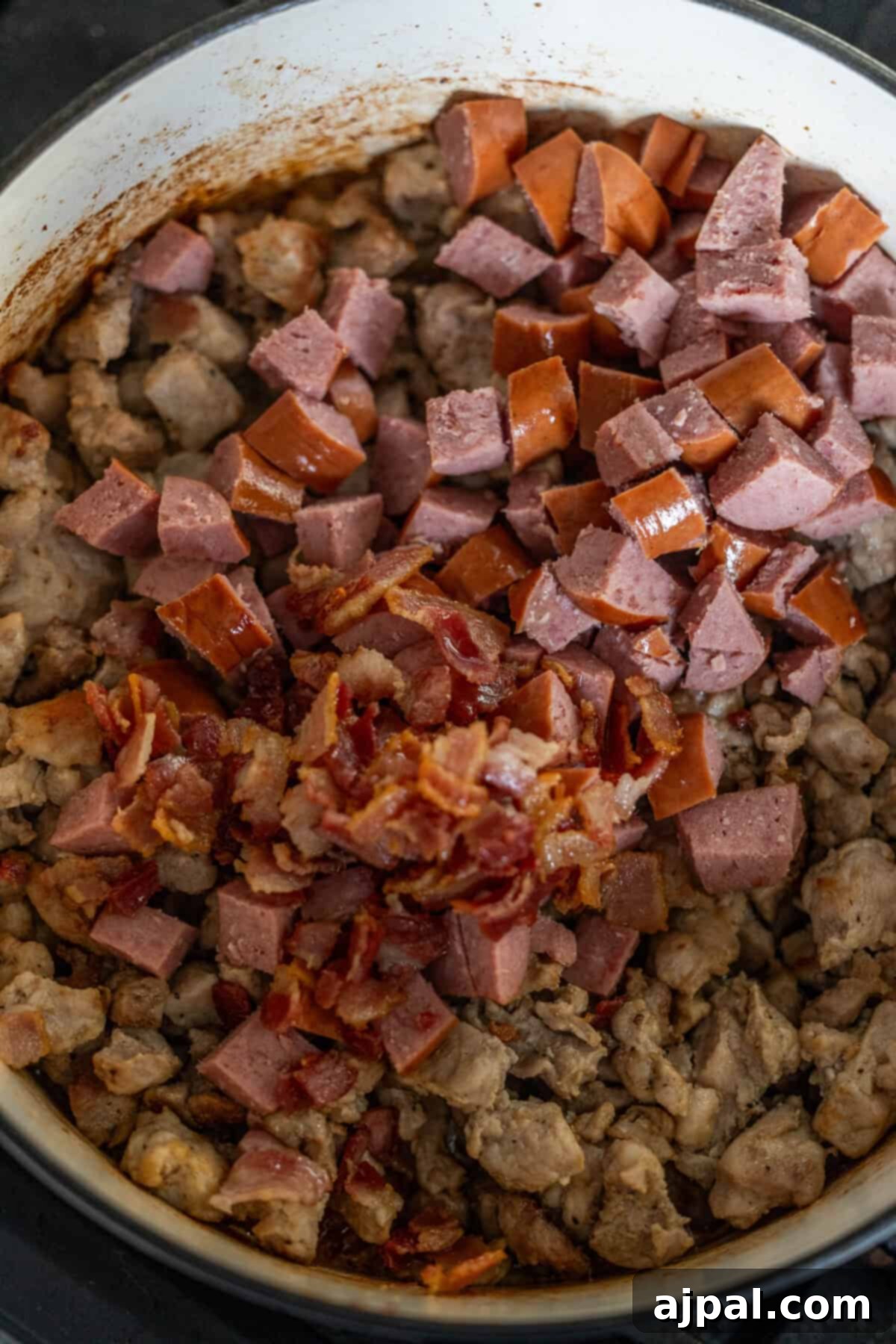 Simmering chopped sausages and bacon pieces with cooked ground meat, forming the savory foundation of a delicious Polish Bigos, or Hunter's Stew.