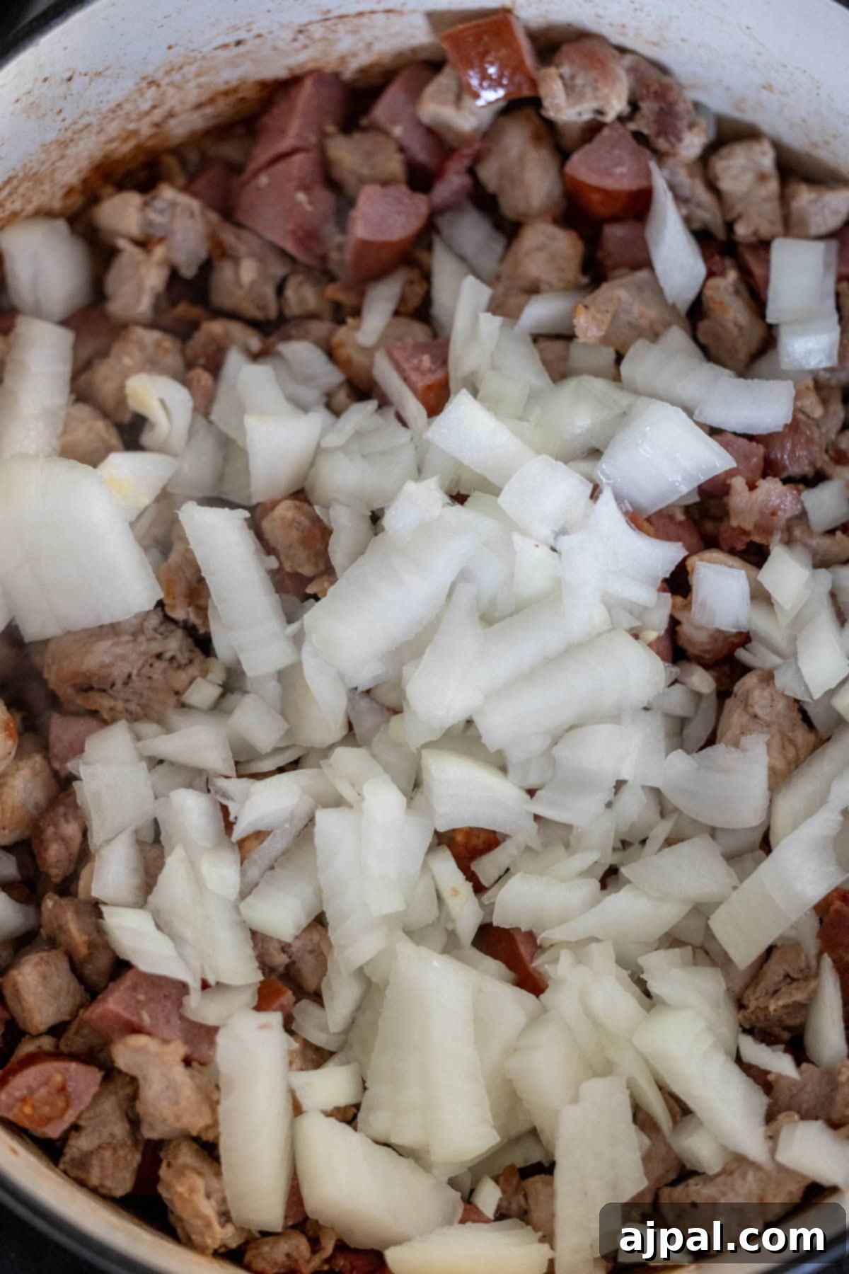 Chopped onions and diced meat gently simmering in a pot, creating the aromatic beginnings of a delightful Polish Bigos stew.