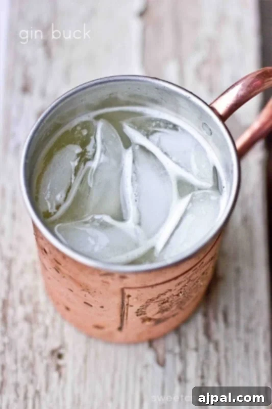 A refreshing Gin Buck cocktail in a gleaming copper mug, filled with ice and garnished with a lime wedge, perfect for summer enjoyment.