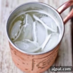 A gin buck in a copper mug filled with ice and a lime garnish.