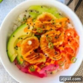 A bowl of rice topped with sliced avocado, fried shrimp with sauce, pickled ginger, shredded vegetables, and black sesame seeds.