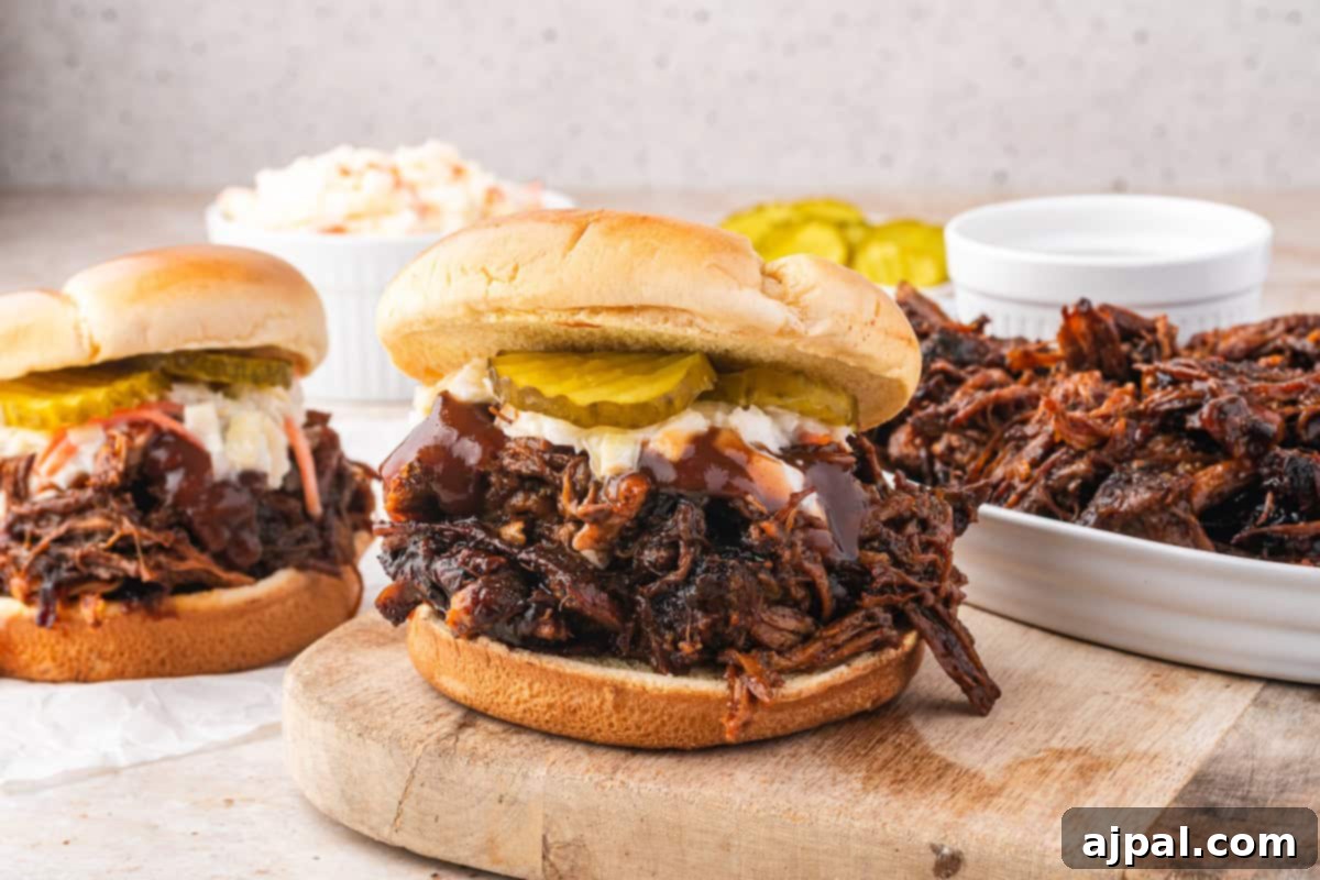 Pulled pork sandwiches with pickles and coleslaw rest on a wooden board, complemented by bowls of extra pulled pork, all slow-cooked to perfection in a Dutch oven.
