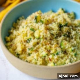 A top-down view of Zucchini Couscous in a bowl, garnished with fresh herbs, showcasing its vibrant colors and fluffy texture.