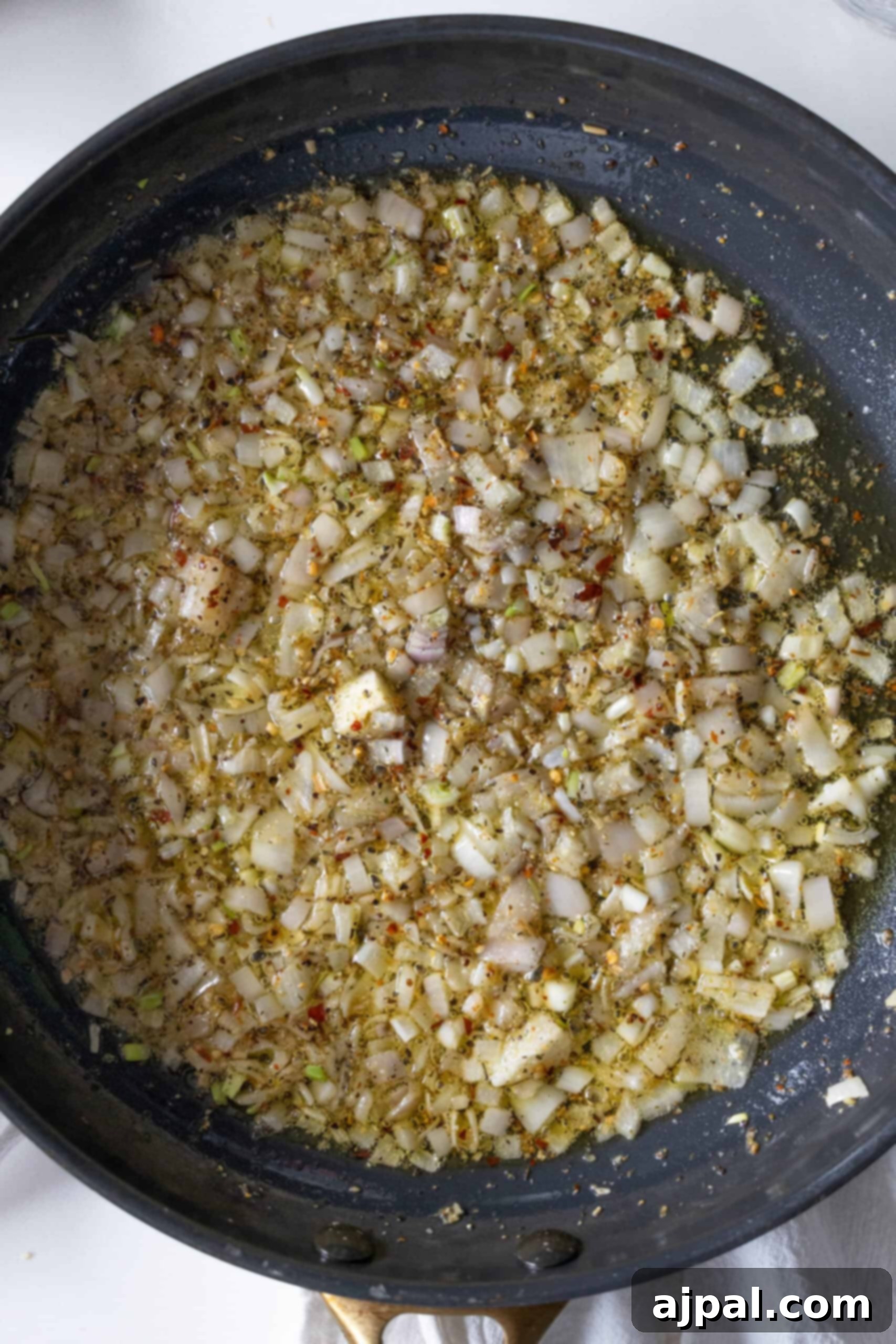 Sautéing shallots and garlic in a pan, preparing the aromatic base for the couscous.