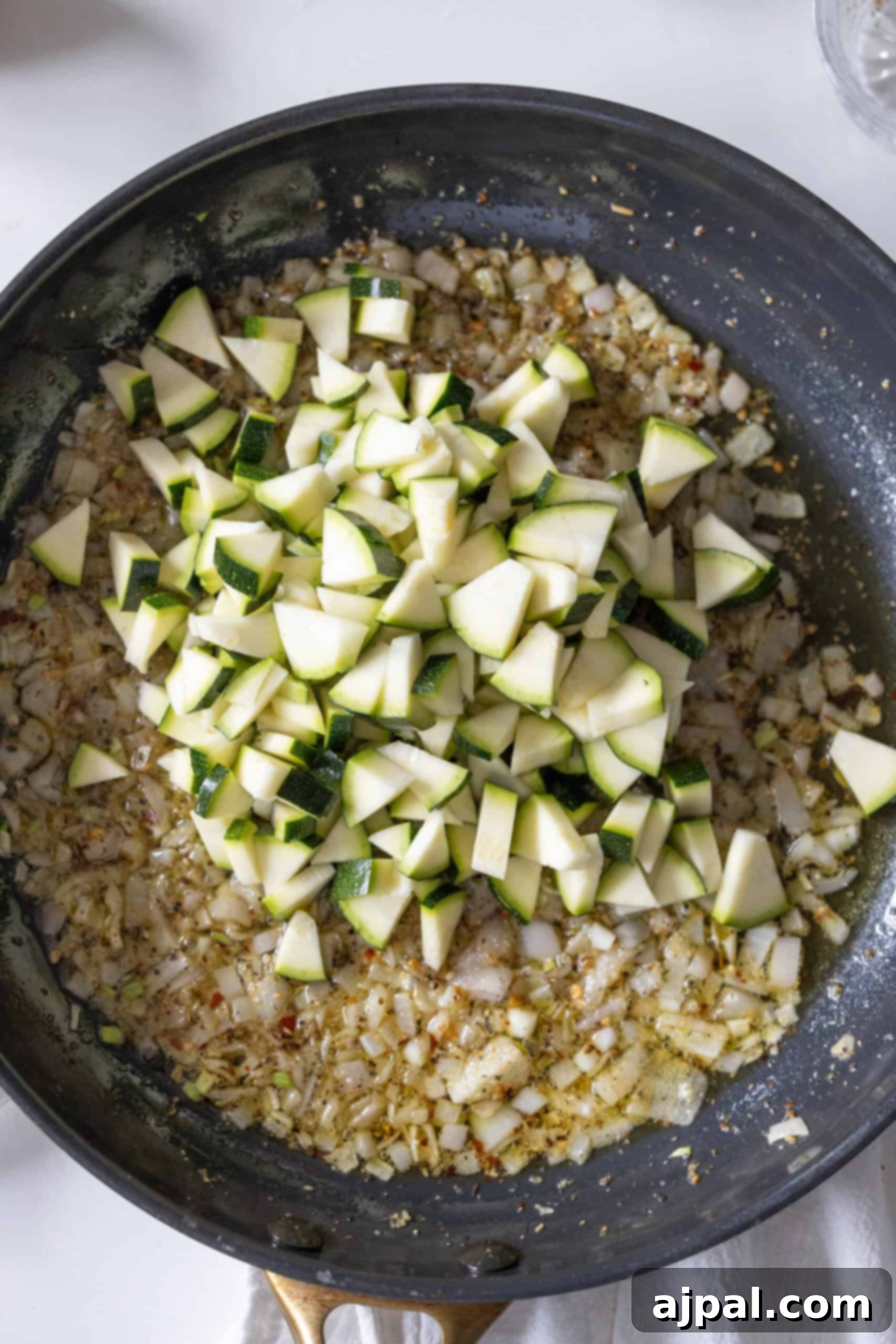 Freshly chopped zucchini ready to be added to the pan with sautéed aromatics.
