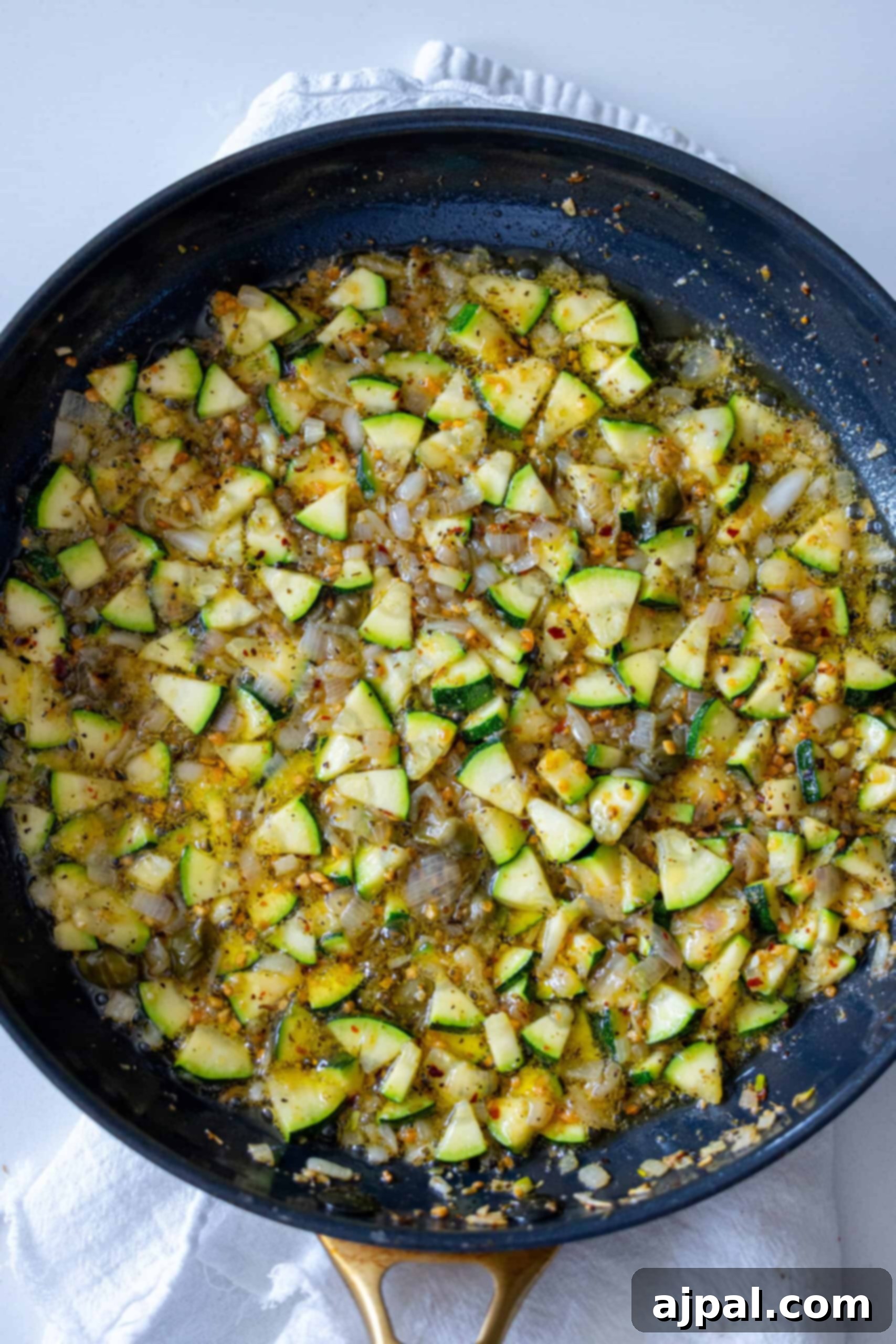 A mix of zucchini and seasoning in a pan, ready for the next step.