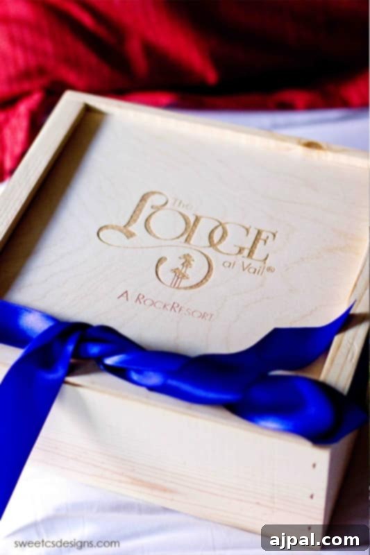Parents' Vail Escape 8 A tastefully arranged wooden box with 'The Lodge at Vail, a Rock Resort' delicately written on it, adorned with a blue ribbon, hinting at special, luxurious touches for a parents' getaway.
