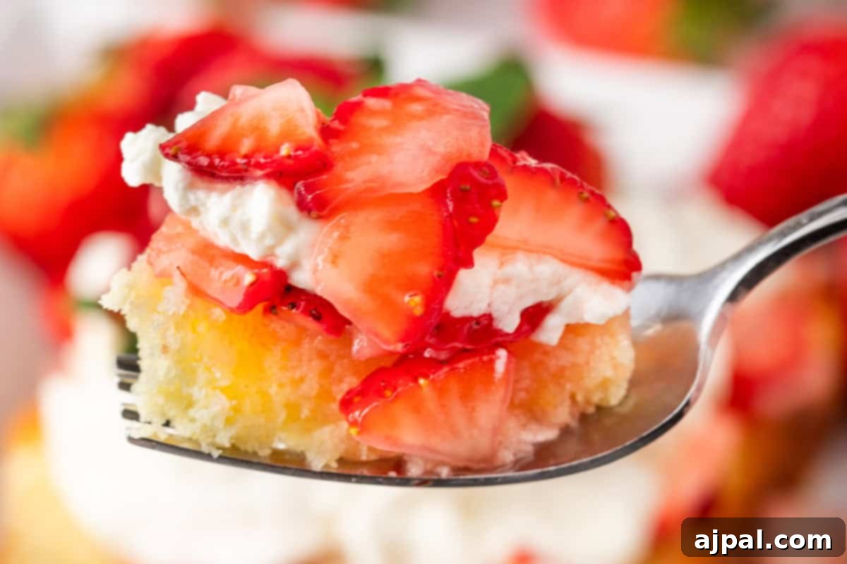 Summer Berry Shortcake 3 A delightful spoonful of cake featuring strawberry shortcake with sliced strawberries and whipped cream.