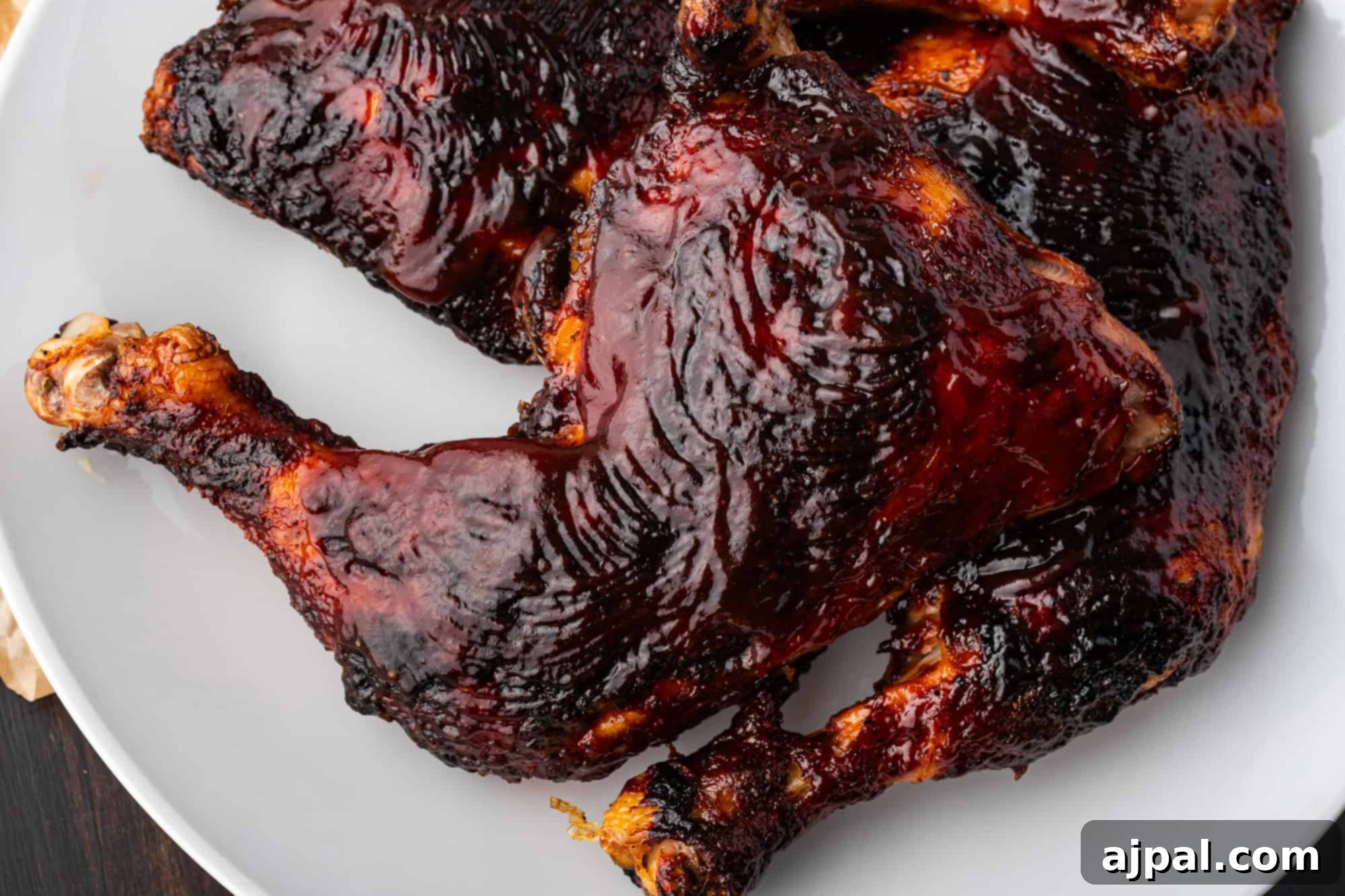 Juicy BBQ Chicken Quarters 14 A close-up of succulent chicken legs with a dark, glossy BBQ glaze sits enticingly on a gray plate.