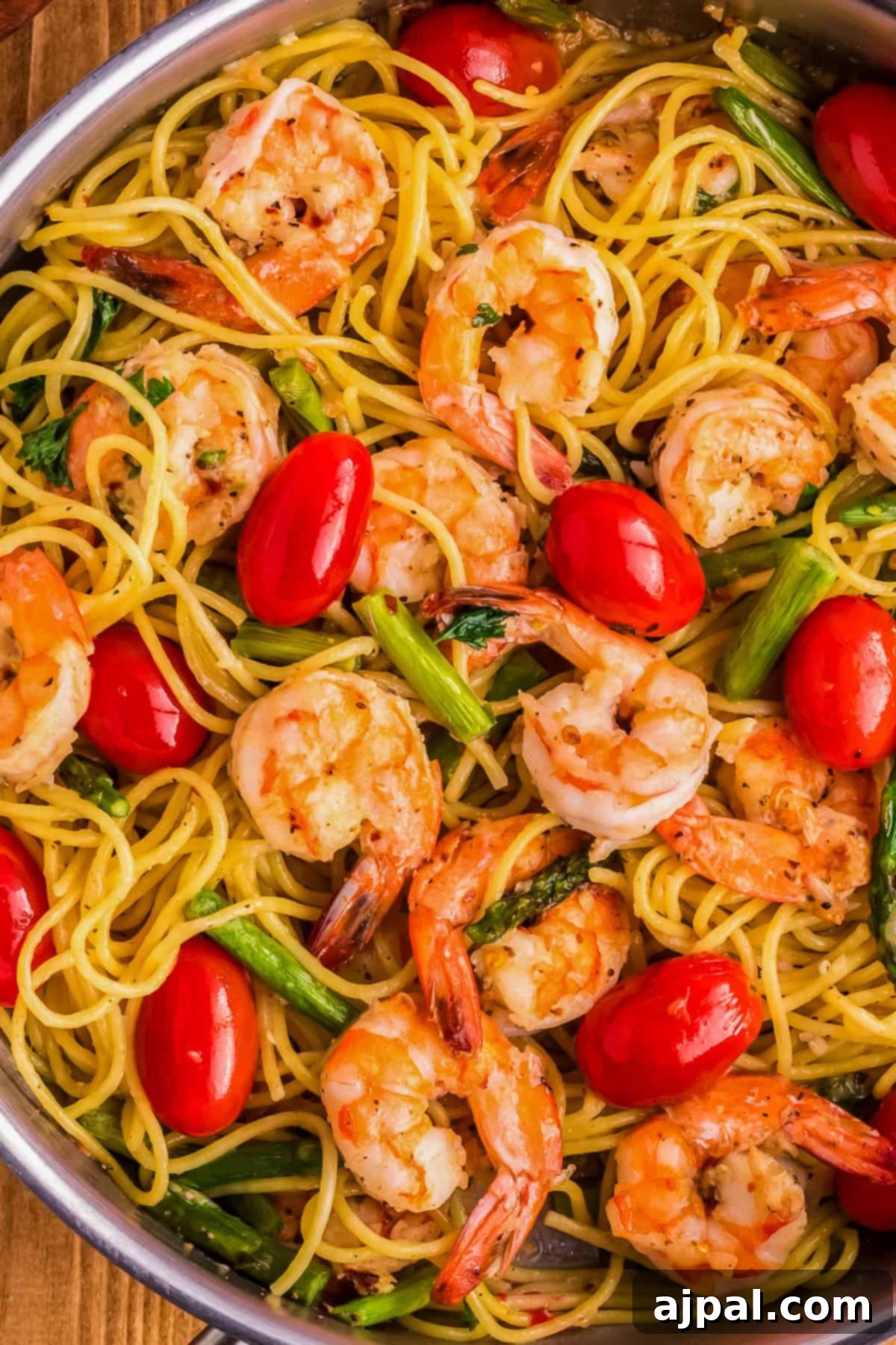 Lemon Garlic Shrimp Pasta 5 A close-up of a pan filled with perfectly cooked pasta featuring succulent shrimp, vibrant cherry tomatoes, and tender asparagus subtly infused with the rich aroma of garlic.