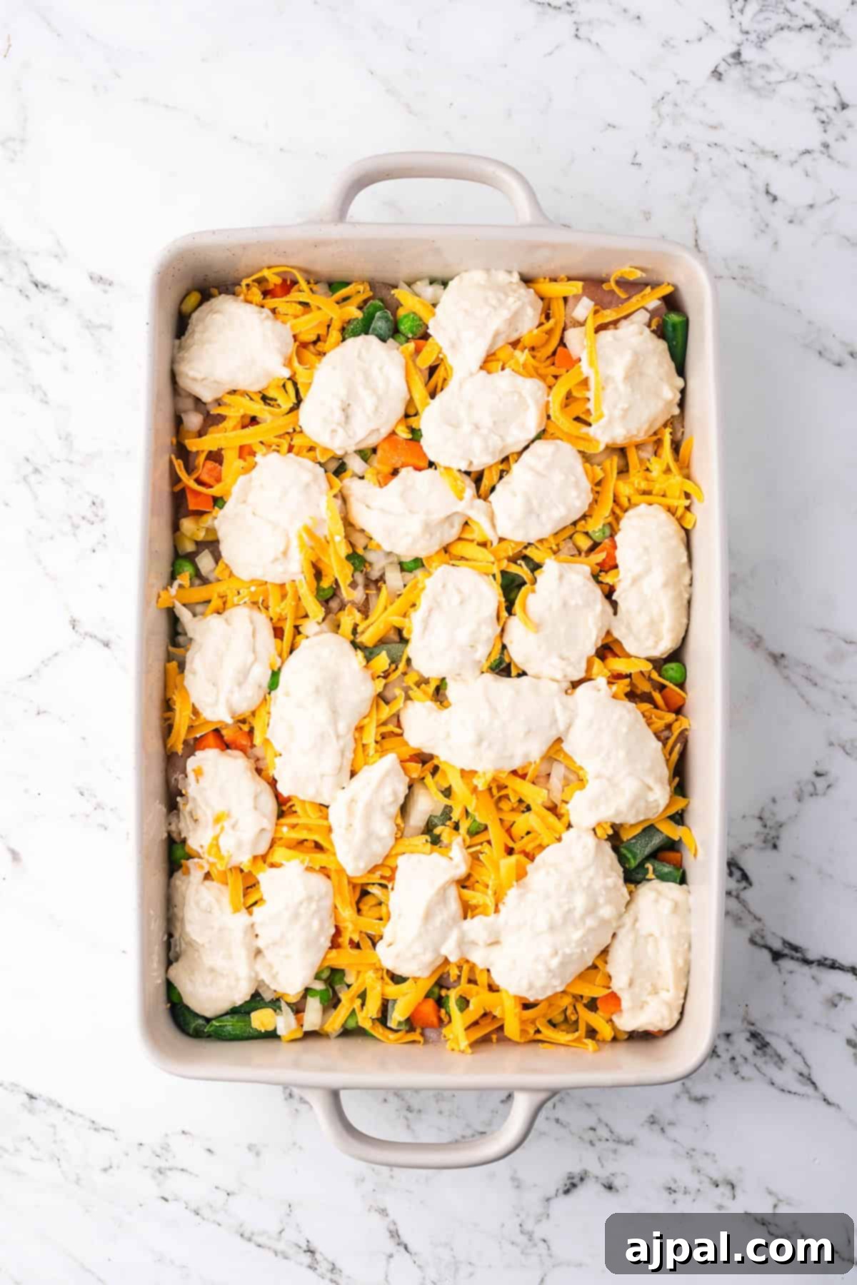 Comforting Chicken and Dumpling Bake 8 Spoonfuls of biscuit dough are dropped over the cheese and vegetable layers in a baking dish, forming the topping for a comforting casserole.