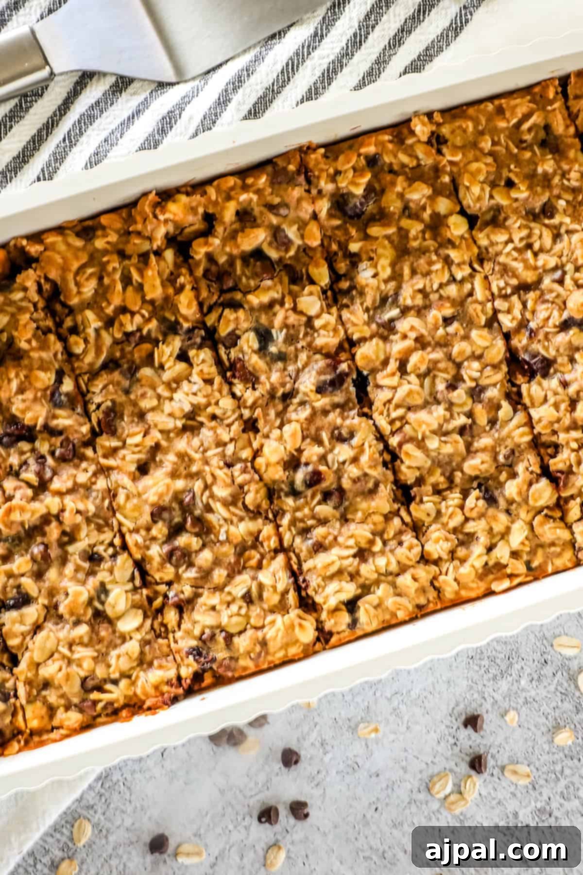 Artisan Sourdough Granola Bites 7 A tray of sourdough granola bars cut into rectangular pieces, with visible oats and bits of dried fruit on top.