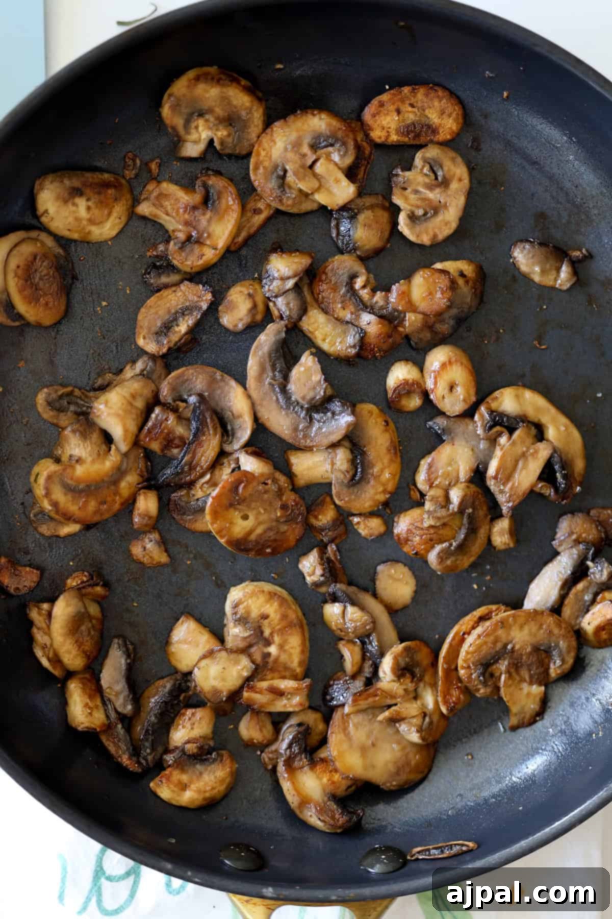 Mediterranean Vegan Sabich Bowls 8 In a black frying pan, sautéed sliced mushrooms are evenly spread and browned to perfection, lending a savory touch to your Vegan Sabich Bowl.