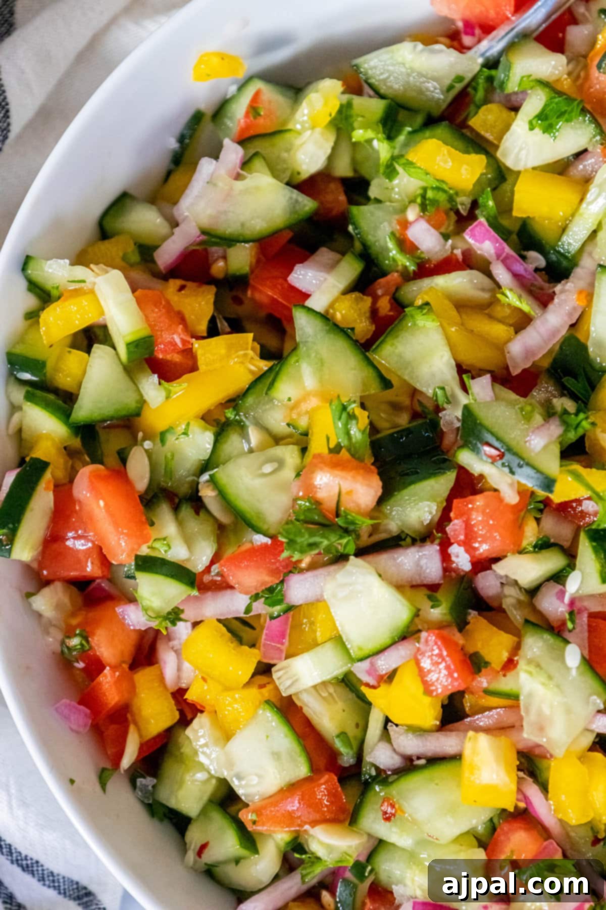 Mediterranean Vegan Sabich Bowls 10 Vegan Israeli salad in a white bowl with a spoon.