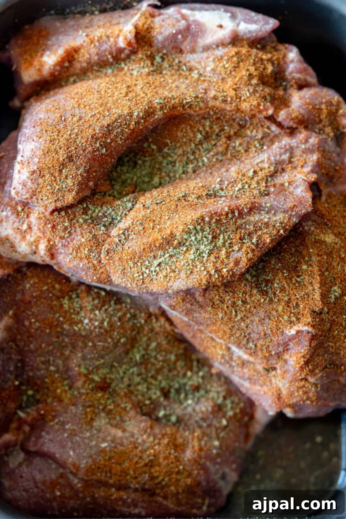 Perfectly Tender Crispy Slow Cooker Carnitas 4 Raw cuts of pork, meticulously seasoned with a vibrant mixture of dry spices and herbs, are carefully layered in a dish. This creates the foundational base for incredibly flavorful Slow Cooker Carnitas, ensuring every bite is rich with taste.