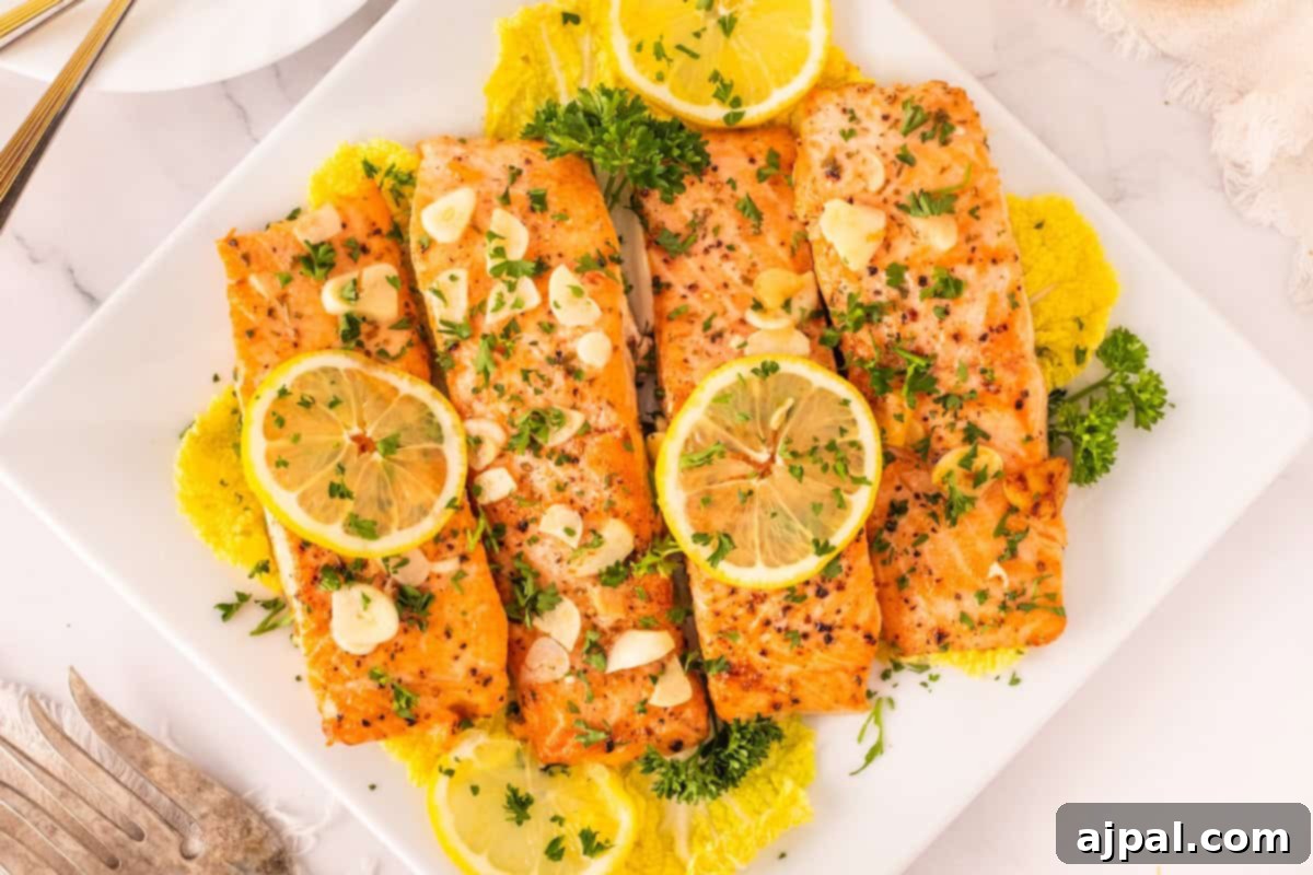 Three baked salmon fillets garnished with lemon slices, fresh parsley, and thinly sliced garlic, elegantly served on a pristine white plate with a side of vibrant leafy greens, showcasing the perfect main course.