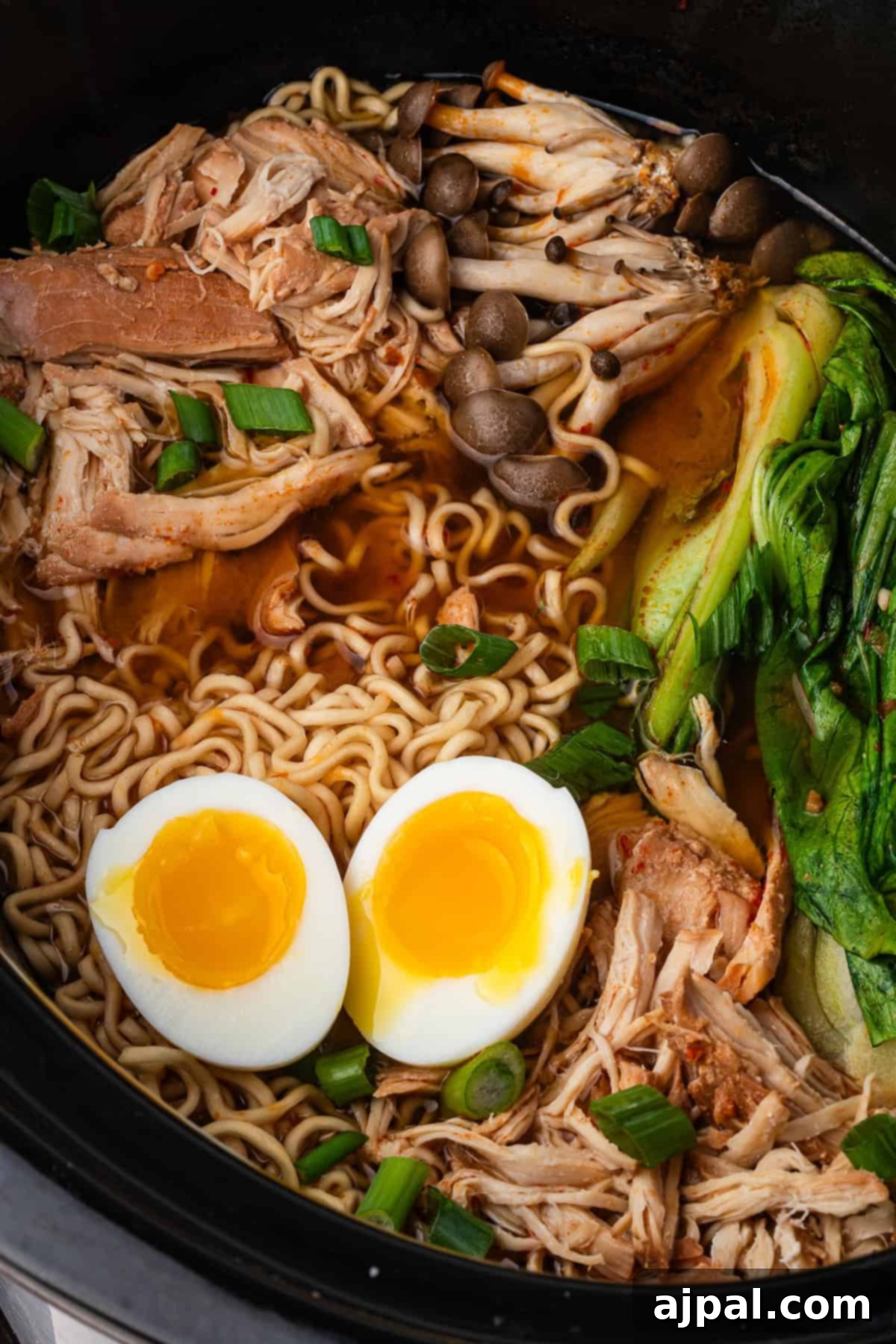 Bowl of Chicken Ramen with shredded chicken, soft-boiled egg halves, bok choy, mushrooms, green onions, and noodles in savory broth—perfectly made as a comforting Slow Cooker Ramen.