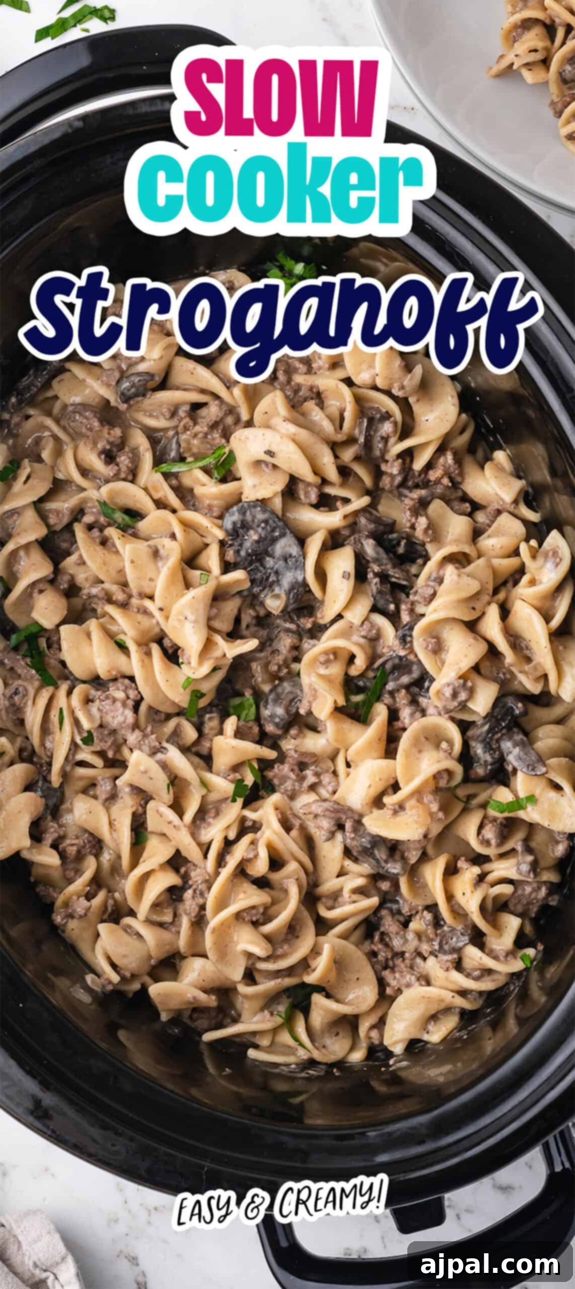 Overhead view of Slow Cooker Beef Stroganoff with egg noodles, mushrooms, and creamy sauce in a slow cooker, topped with a text overlay reading "Slow Cooker Stroganoff.