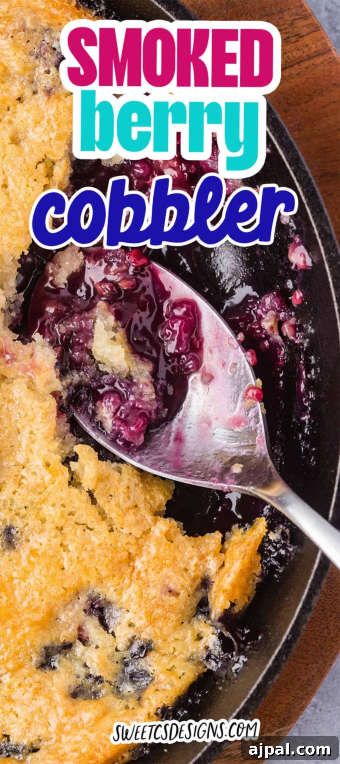 A close-up of Smoked Berry Cobbler in a cast iron skillet, with a serving spoon scooping out a portion of the warm, smoky dessert.
