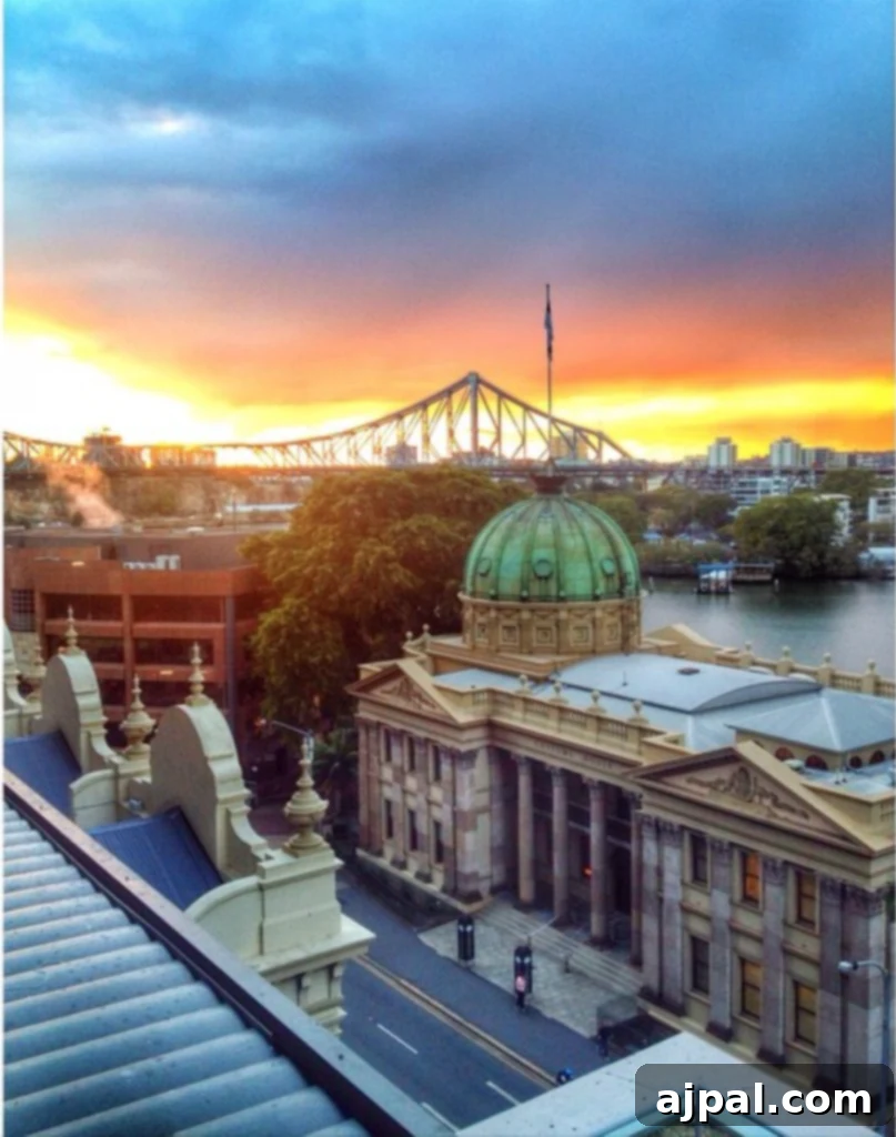 Experience Brisbane Australia 2 Stunning panoramic view of Brisbane city at sunset from the Oaks Aurora Hotel, featuring the winding river and illuminated Story Bridge. Ideal for travelers planning their Brisbane tour.
