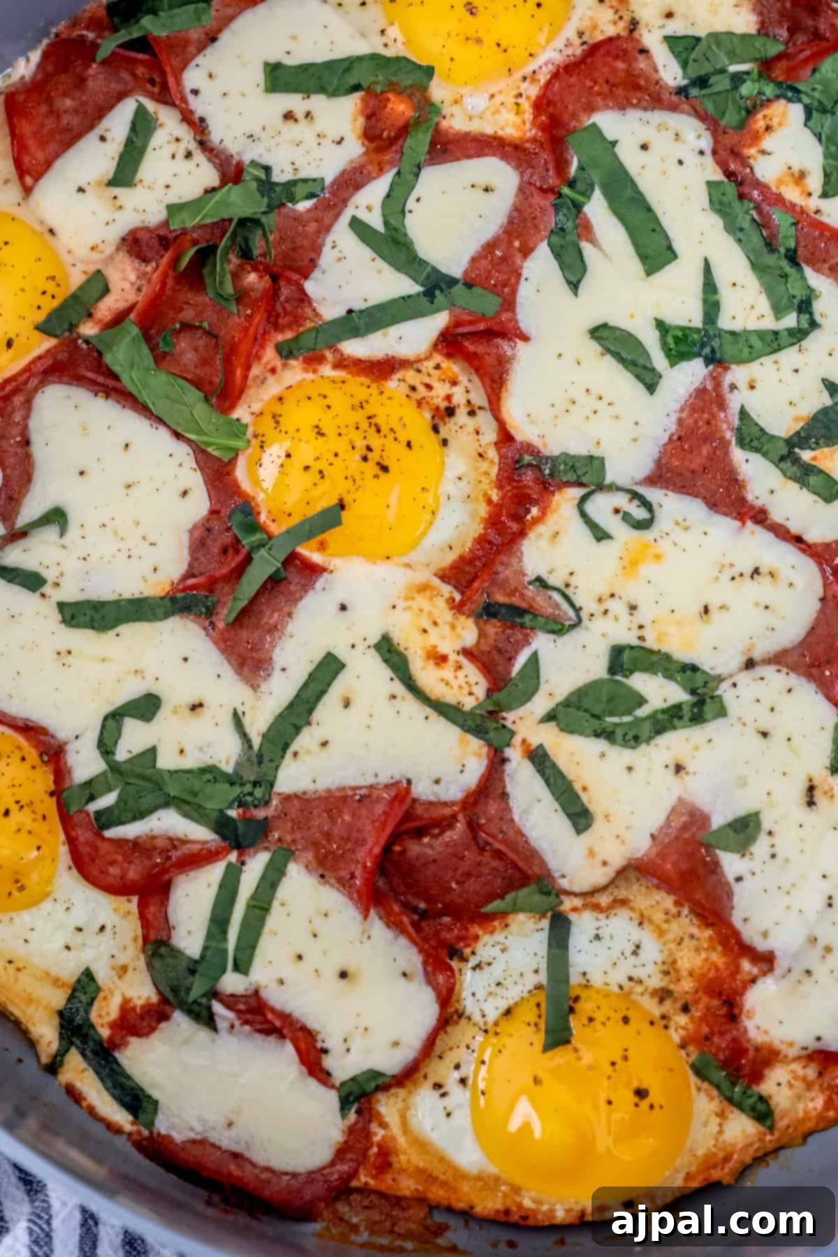 Close-up of a keto breakfast pizza topped with perfectly cooked sunny-side-up eggs, melted mozzarella cheese, vibrant tomato sauce, spicy pepperoni slices, and fragrant fresh basil.