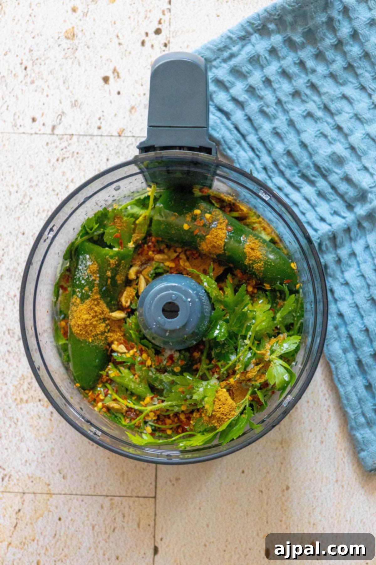 Zesty Zhoug Chicken Thighs 6 A food processor filled with fresh green herbs, jalapeños, and garlic, ready to be blended into Israeli cilantro zhoug sauce.