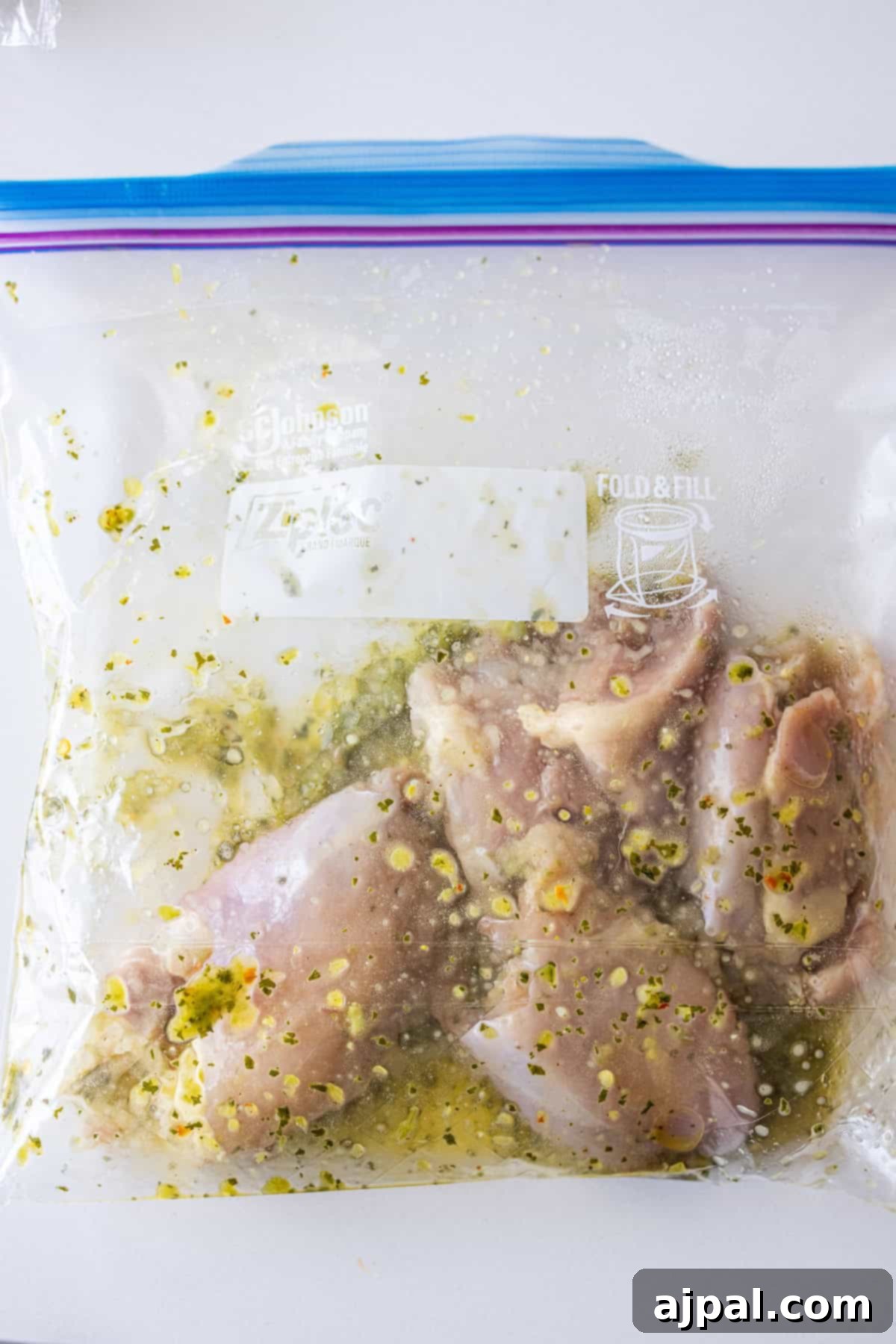 Zesty Zhoug Chicken Thighs 7 Marinating Zhoug chicken pieces are visible inside a sealed plastic zip-top bag, infused with aromatic herbs and seasoning, ready for cooking.