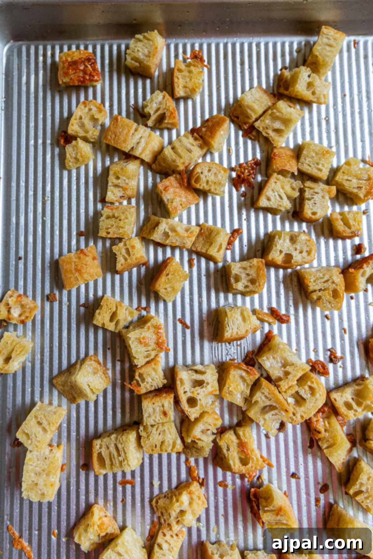 Crunchy Bread Bites 8 Homemade croutons—cubed pieces of toasted bread—are spread out on a ridged metal baking sheet.