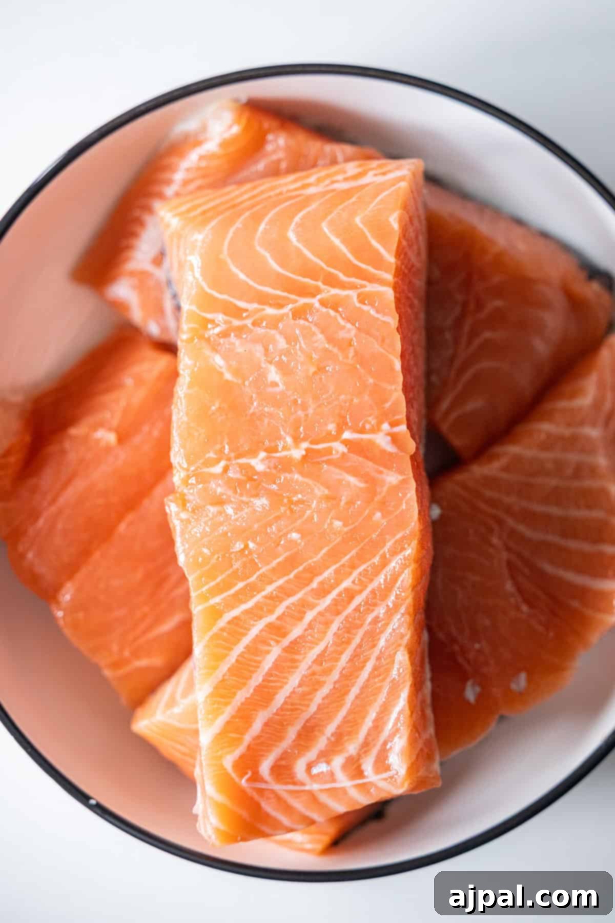 Raw Japanese BBQ Salmon fillets arranged in a white bowl, showcasing the vibrant orange flesh and delicate marbling typical of premium Japanese Salmon.