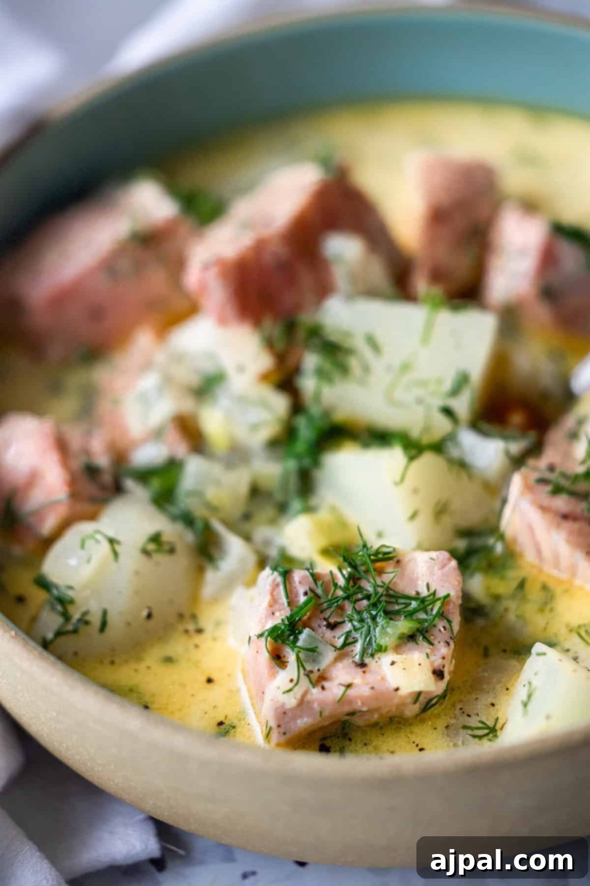 Traditional Finnish Salmon Soup 3 A bowl of creamy Finnish Salmon Chowder, or lohikeitto, featuring chunks of salmon, potatoes, and fresh dill, served in a shallow dish.