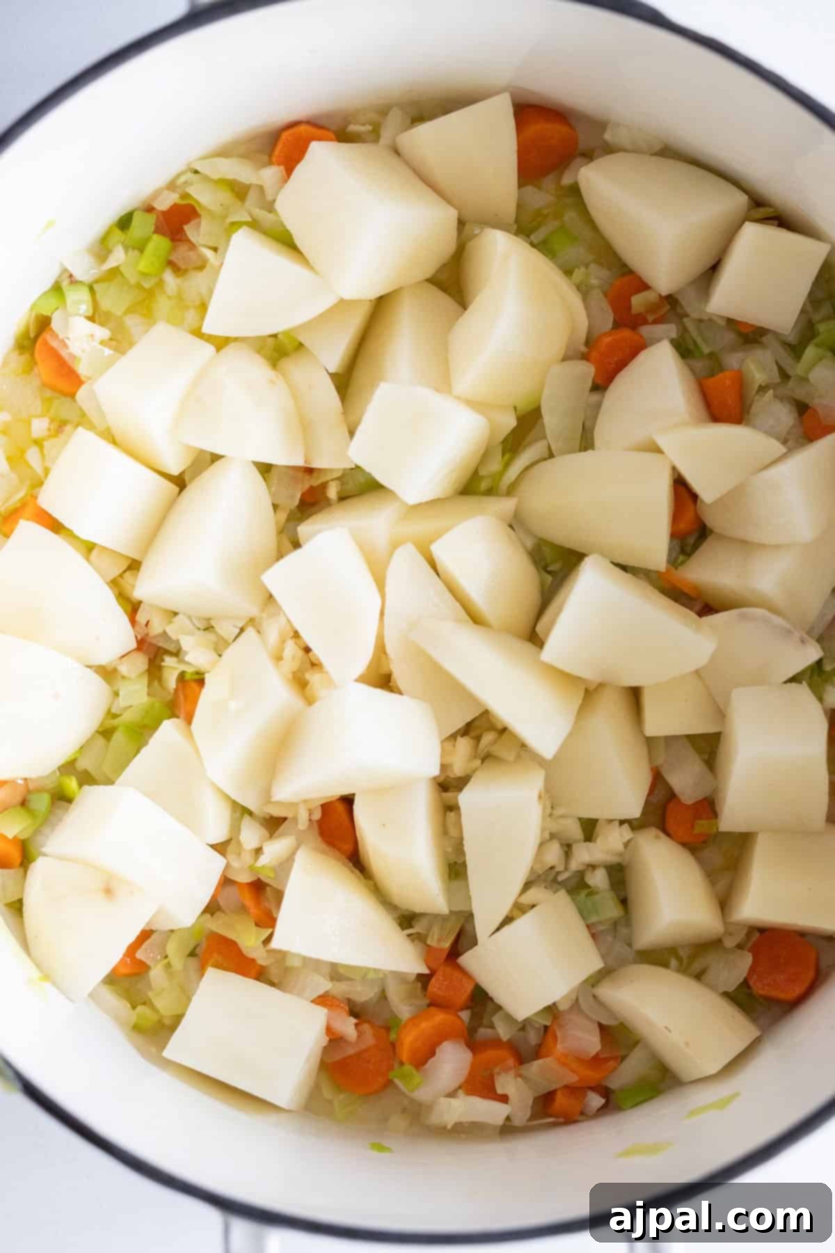Traditional Finnish Salmon Soup 8 Chopped potatoes, carrots, onions, and celery in a white pot, ready to be cooked into a traditional Finnish Salmon Chowder.